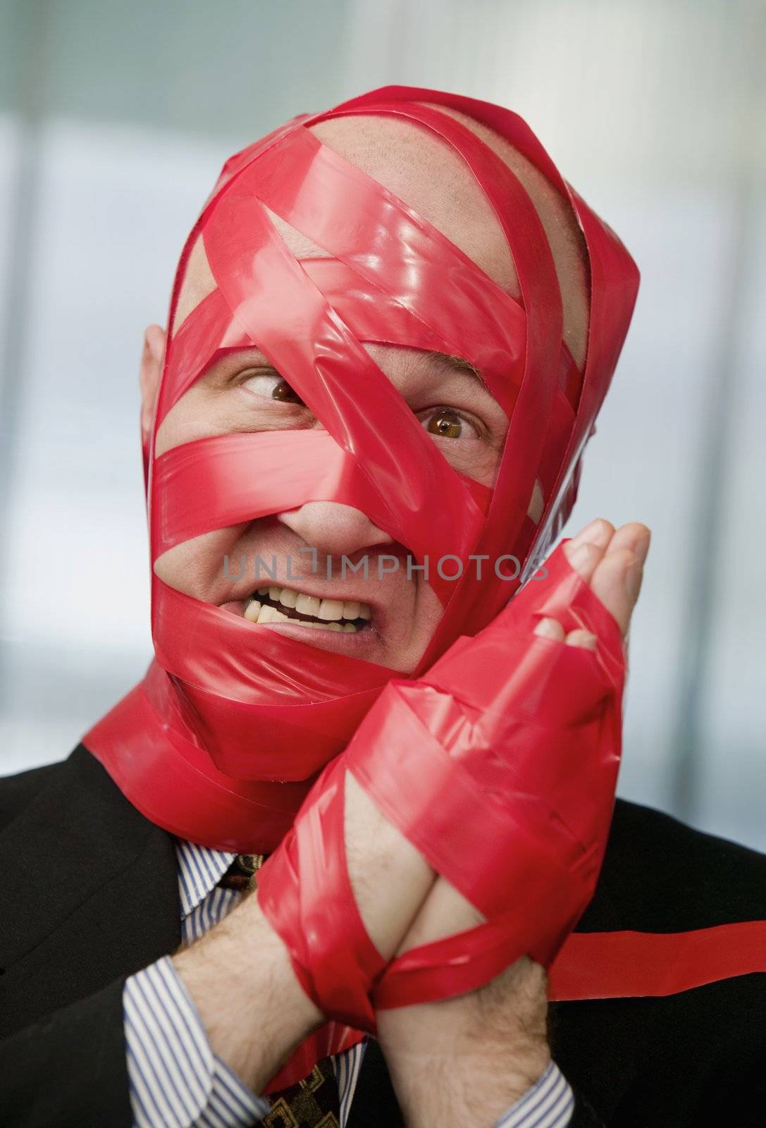 Cross-eyed businessman wrapped in red tape