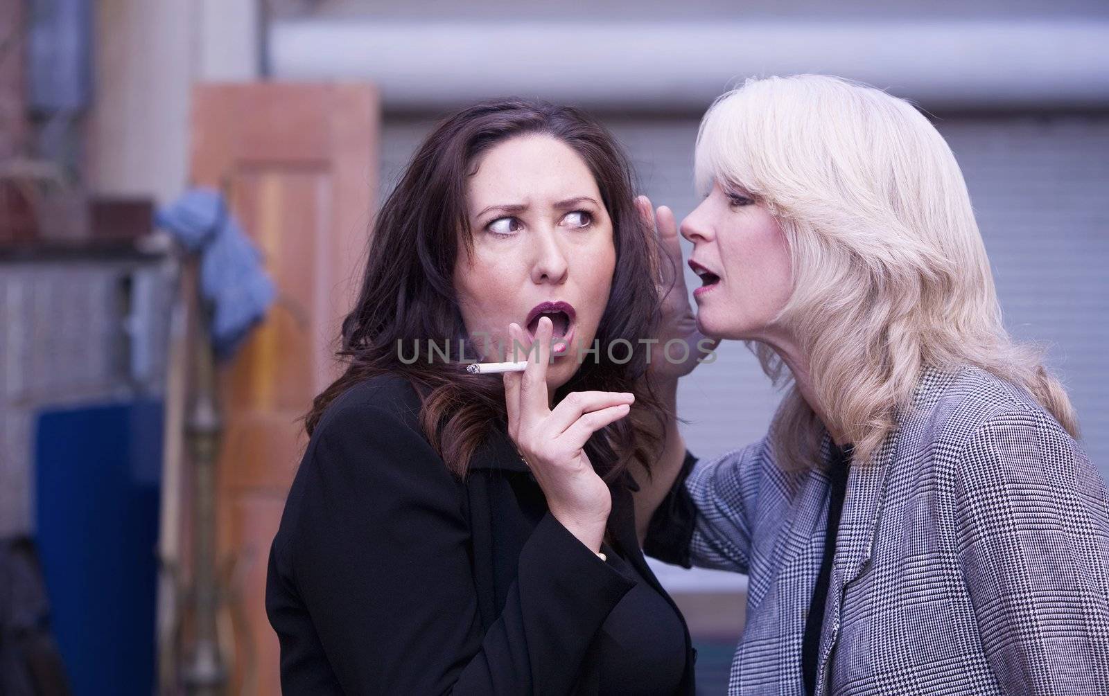 Two women engaging in gossip during a smoking break