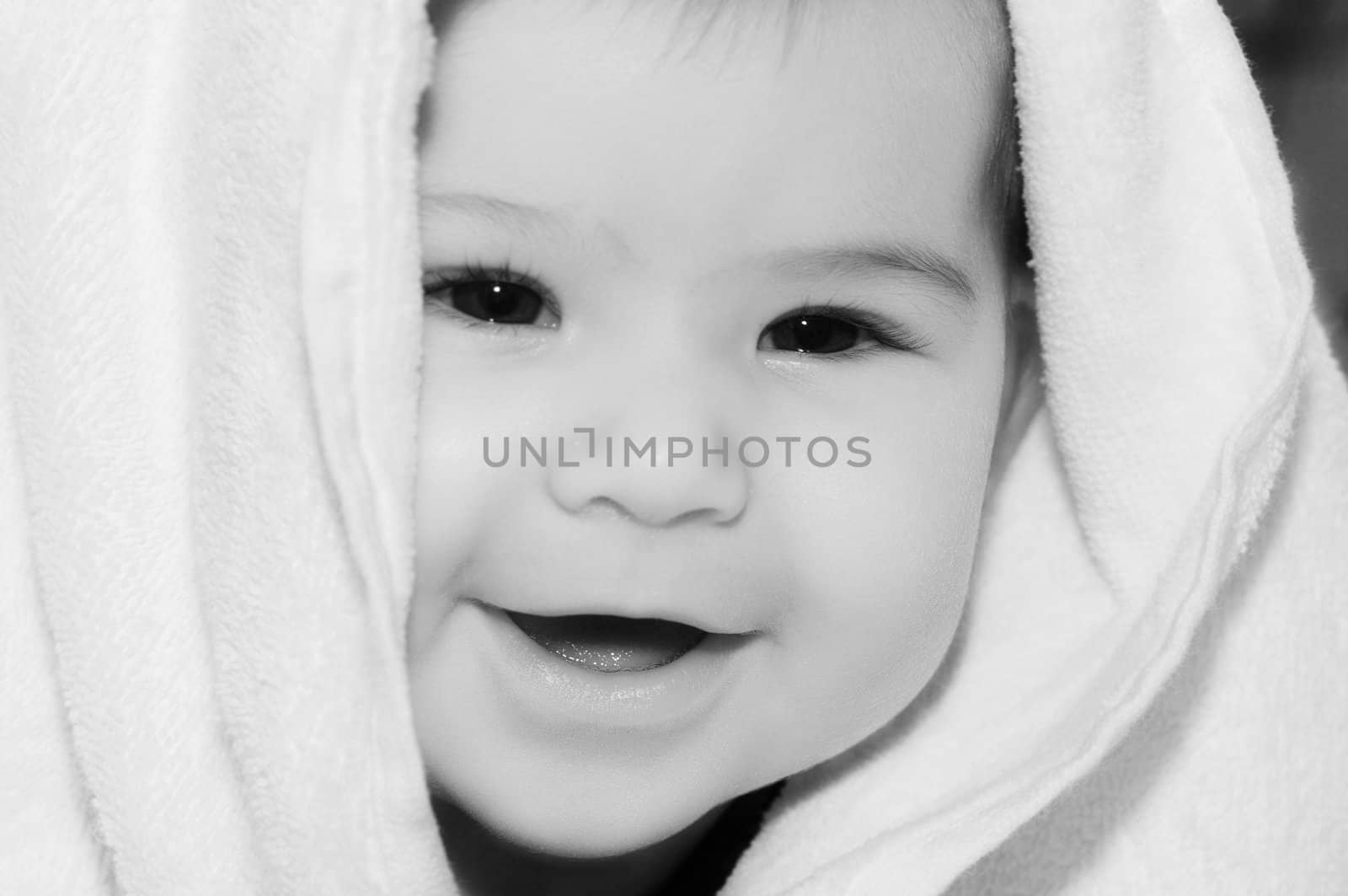 baby looking out and smiling from under blanket by dolnikow