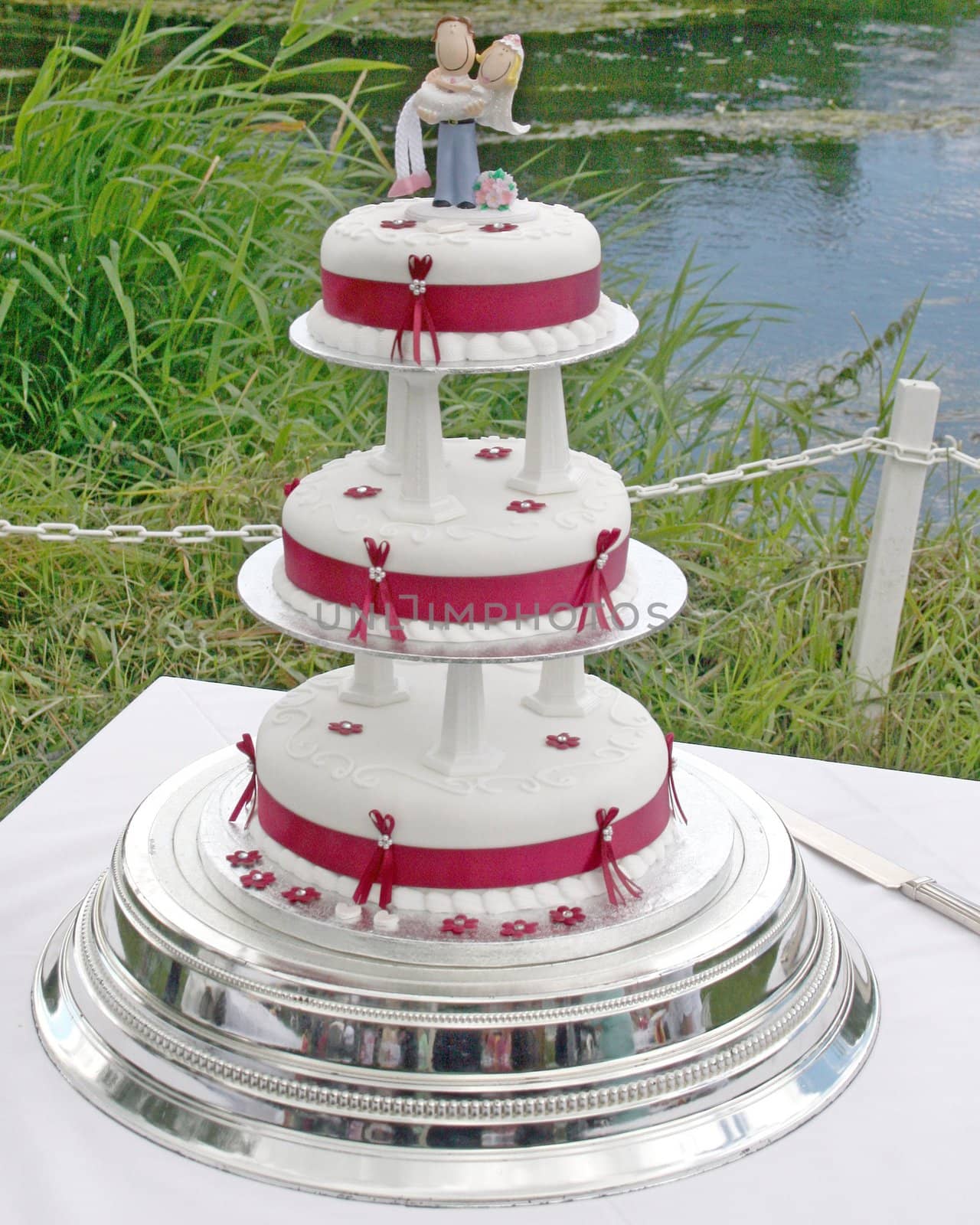 Wedding Cake with Bride and Groom and lake behind.