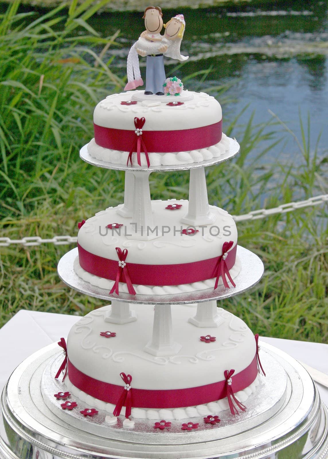 Wedding Cake with Bride and Groom and lake behind.