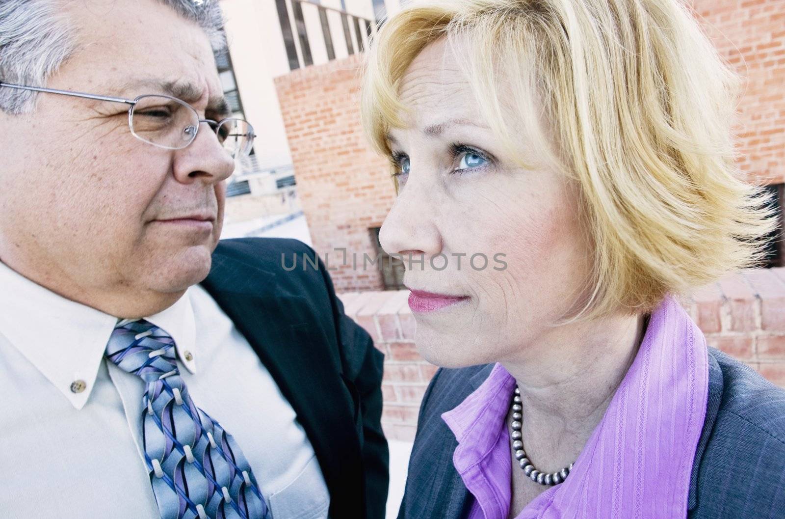 Executive man and woman on a downtown roof with ambiguous expressions