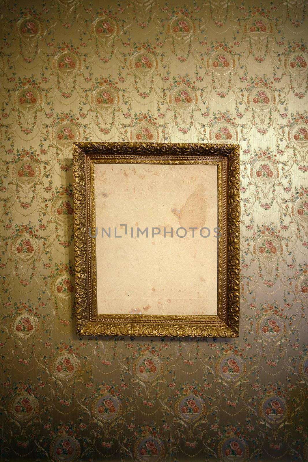 Photo of an antique frame hanging on a wall with vintage wallpaper.
