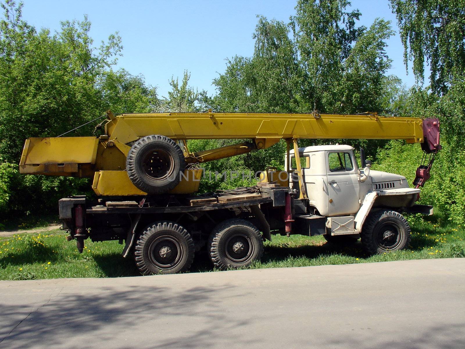 Truck with yellow crane at the grebe field near road