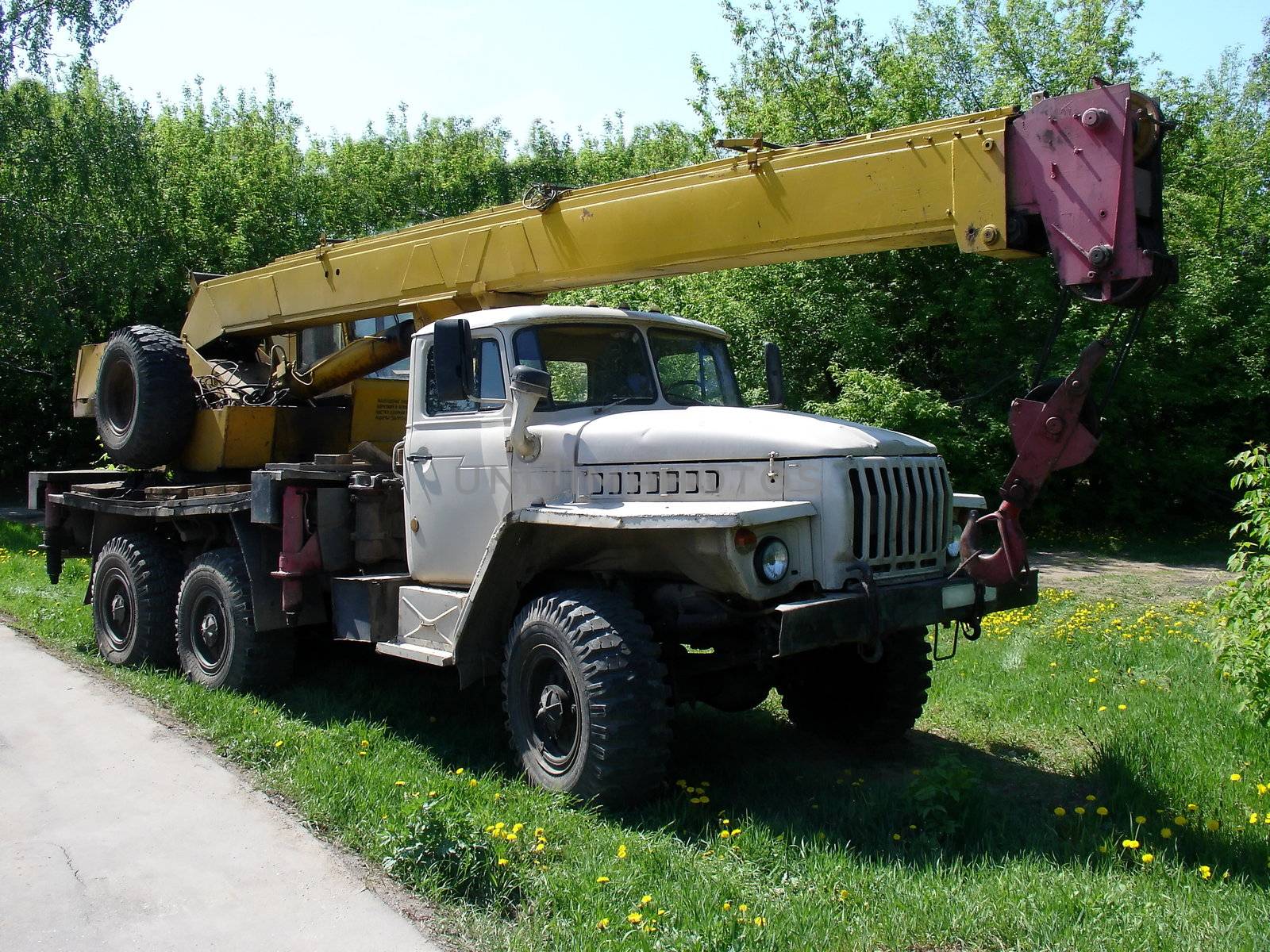 Truck with yellow crane at the grebe field near road