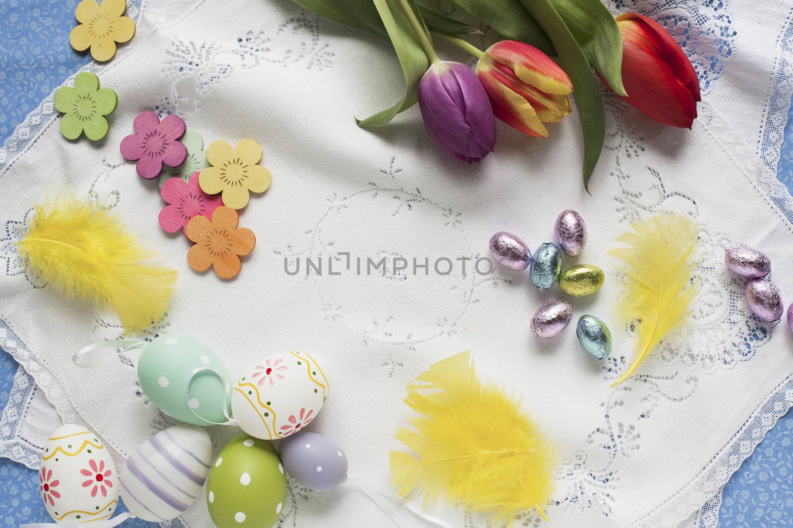 Easter goodies with chocolate eggs wrapped in foil, tulips and decorated eggs.
