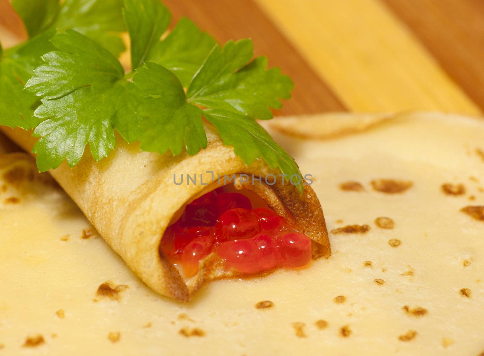 Pancake with red caviar and celery close up