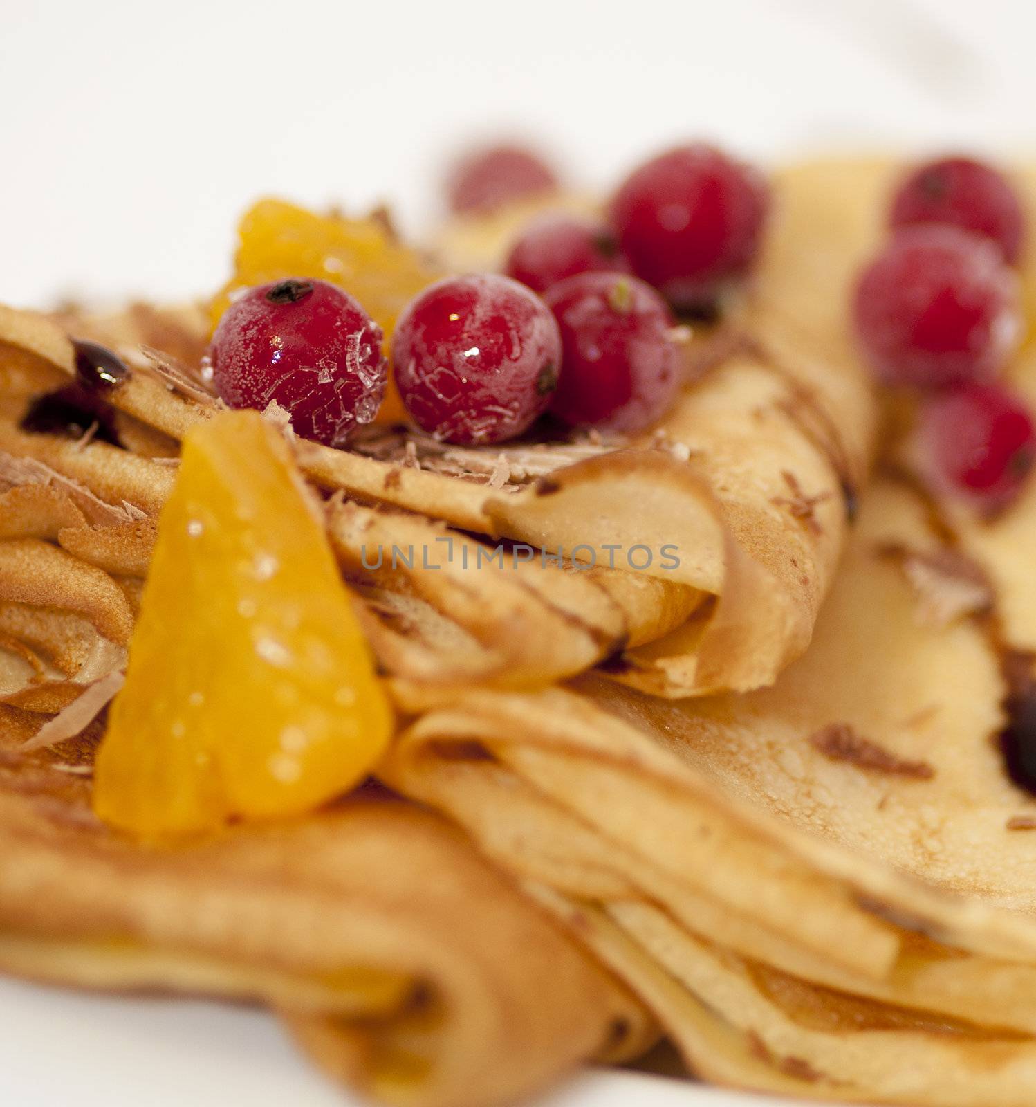 Pancakes with orange, shaving chocolate and red currants close up