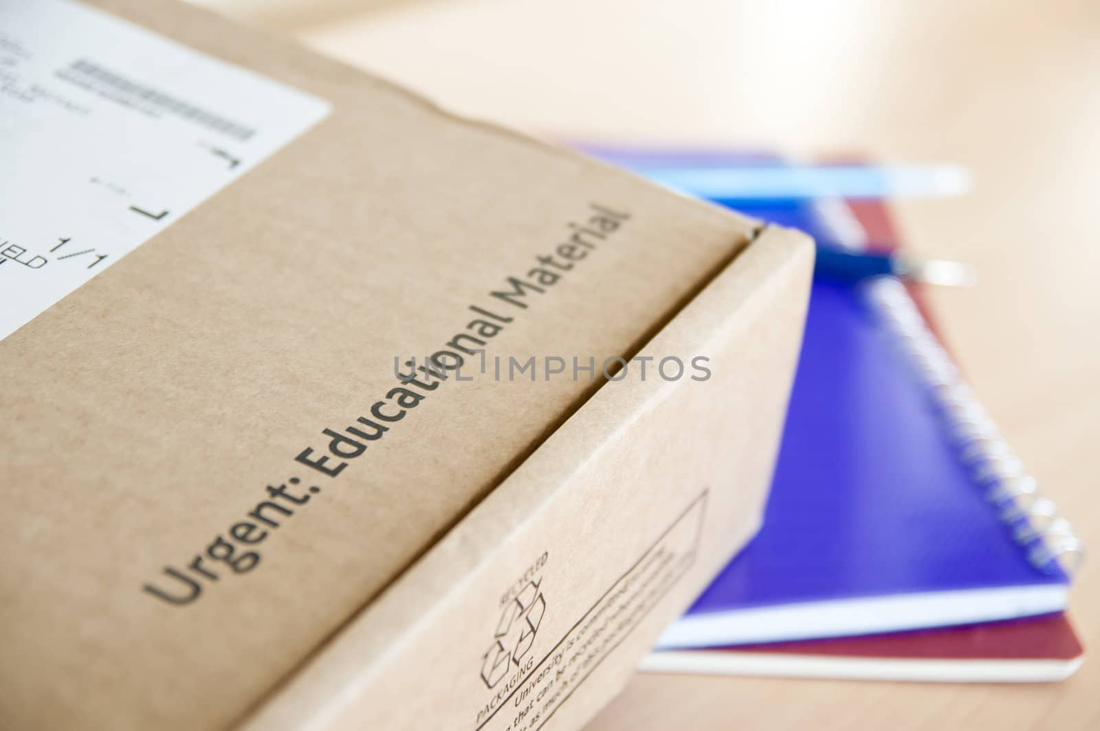 High angle shot of distance learning cardboard box with notebooks underneath.