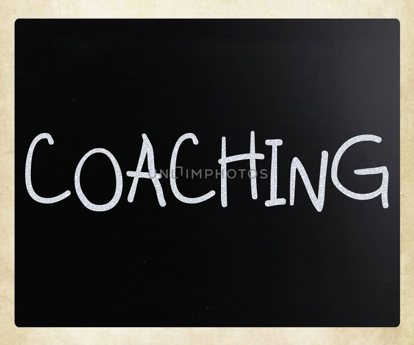"Coaching" handwritten with white chalk on a blackboard