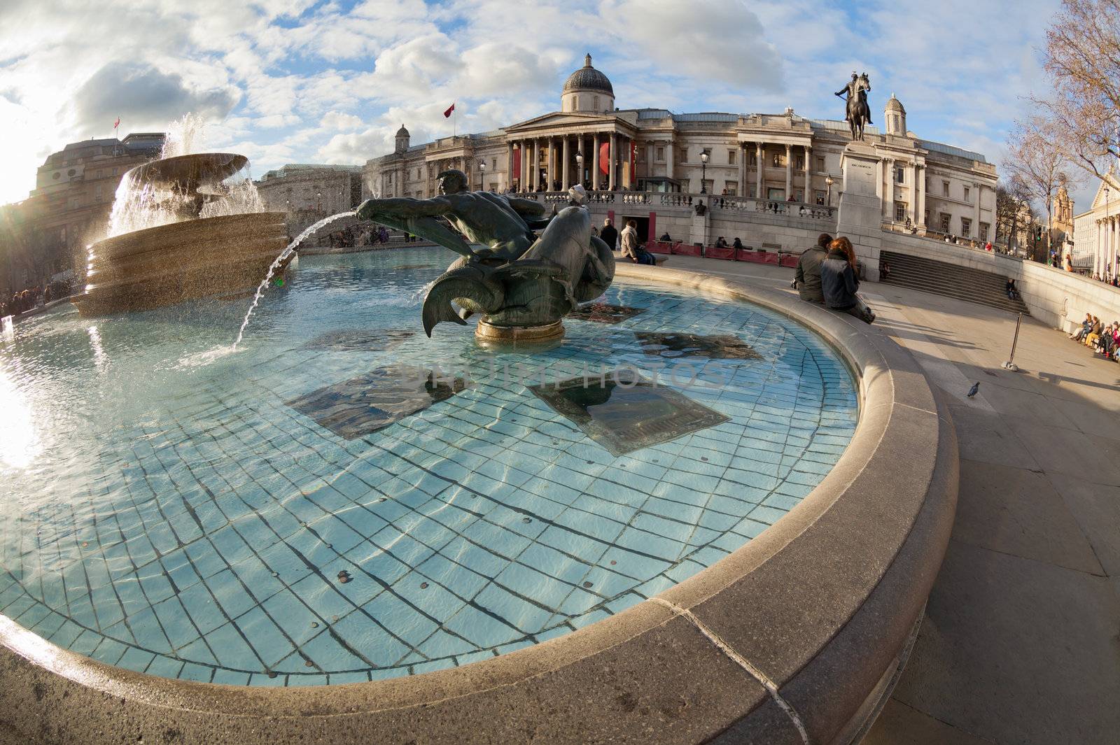 Trafalgar Square fountain in London, United Kingdom. Shot taken fisheye wide angle lens, which highlights the curvilinear architectural forms and round pool fountain in front
