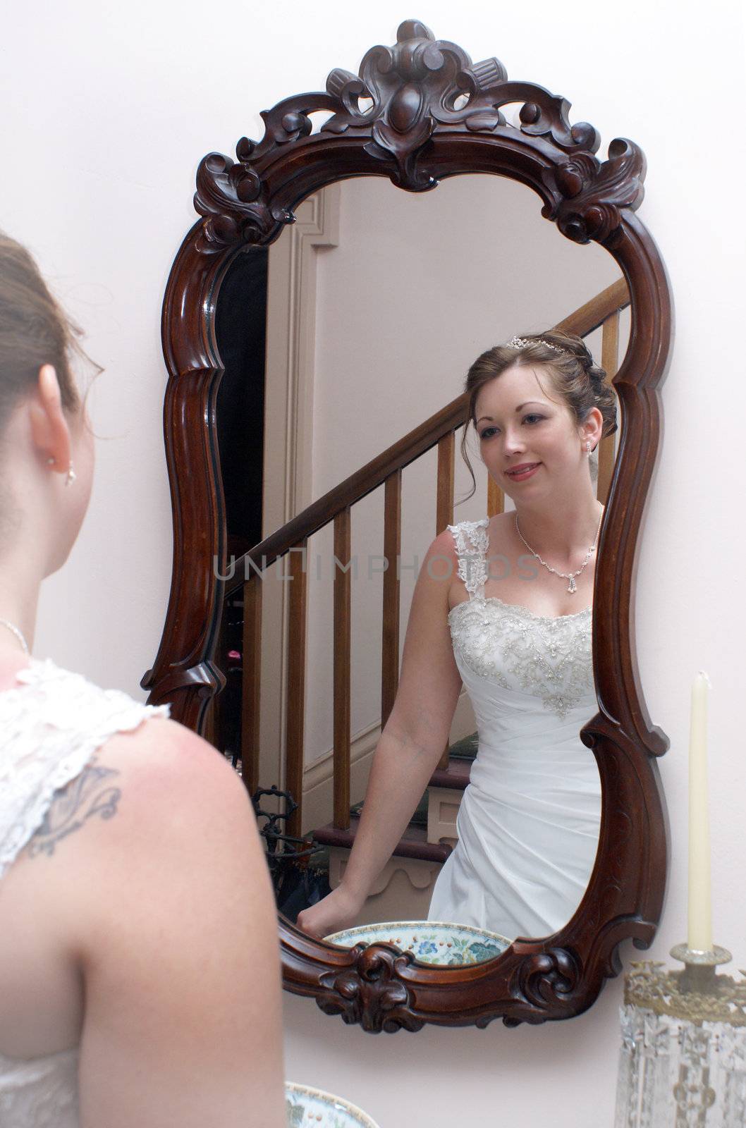 A newly married bride is admiring herself in the mirror on her wedding day.