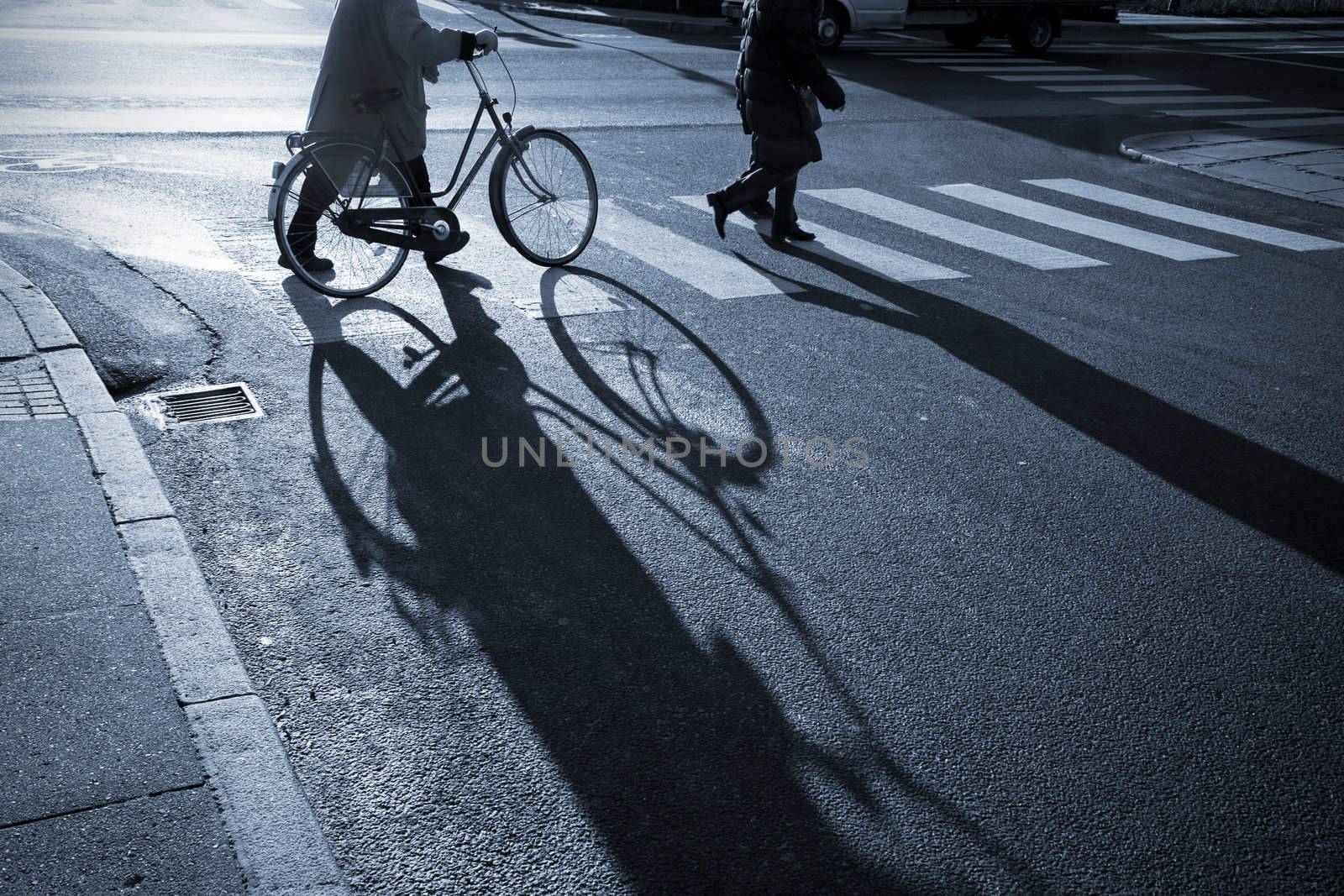 Senior lady with her bicycle in a zebra crossing a cold winter morning in Denmark. Monochrome image.