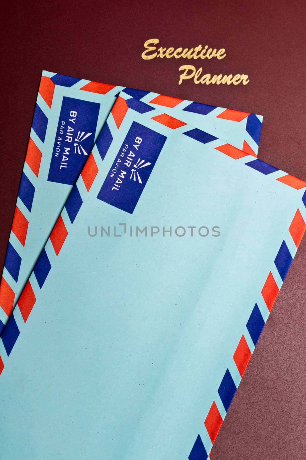 a dark red executive planner with two blue color envelopes in portrait orientation