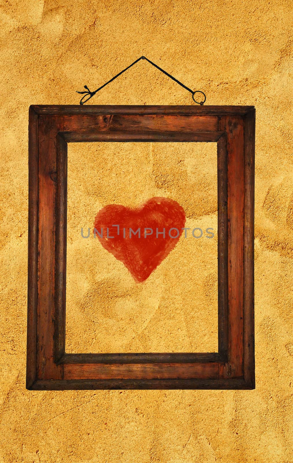 A red heart in an old wooden frame on an old rough wall.