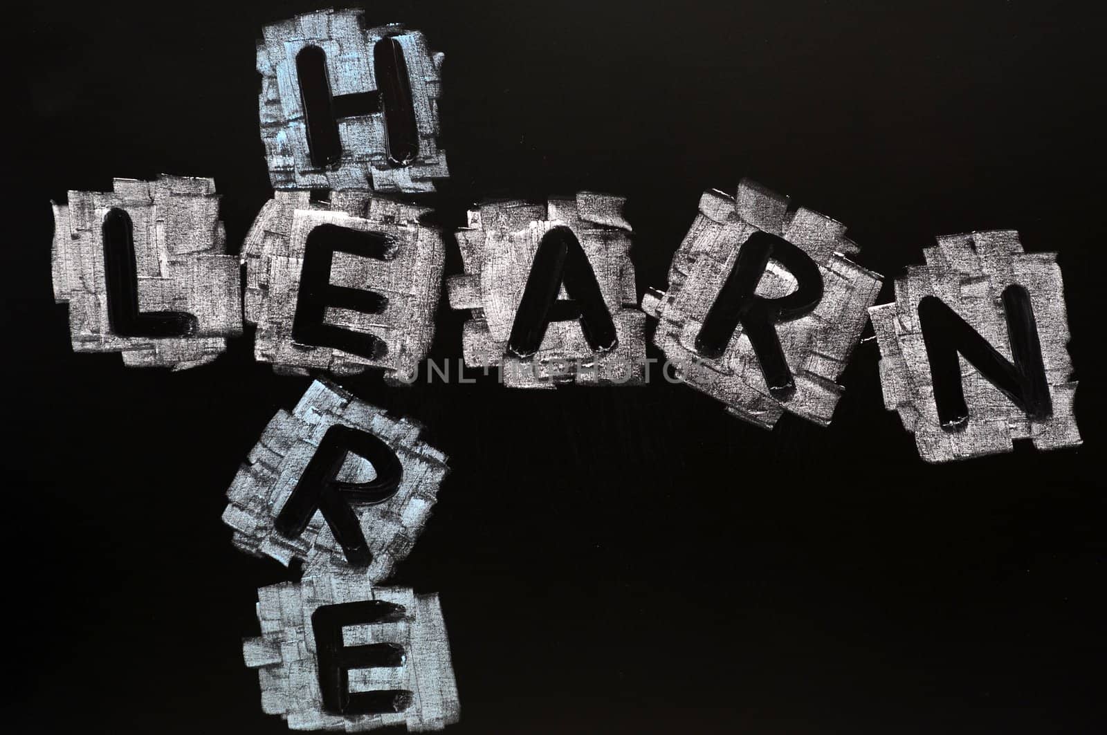 Crossword of Learn Here written in chalk on a blackboard