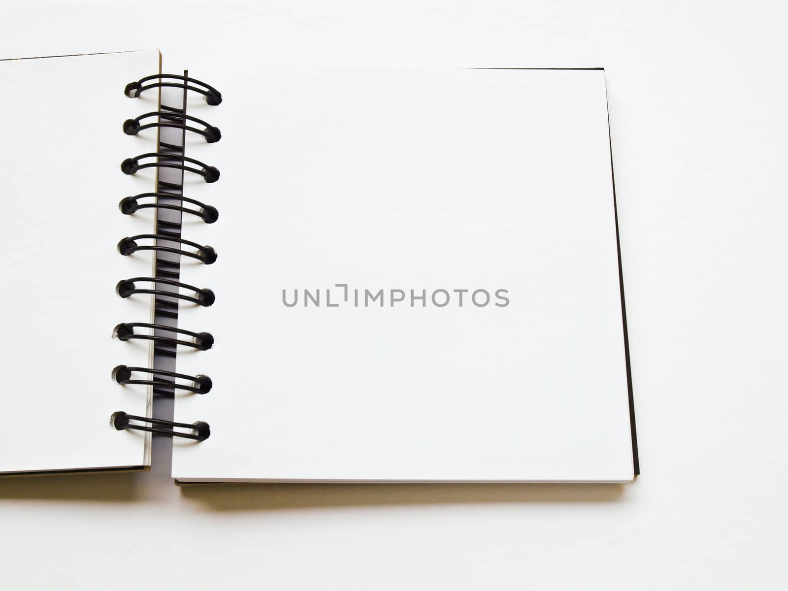 open spiral binding notebook on white by gururugu