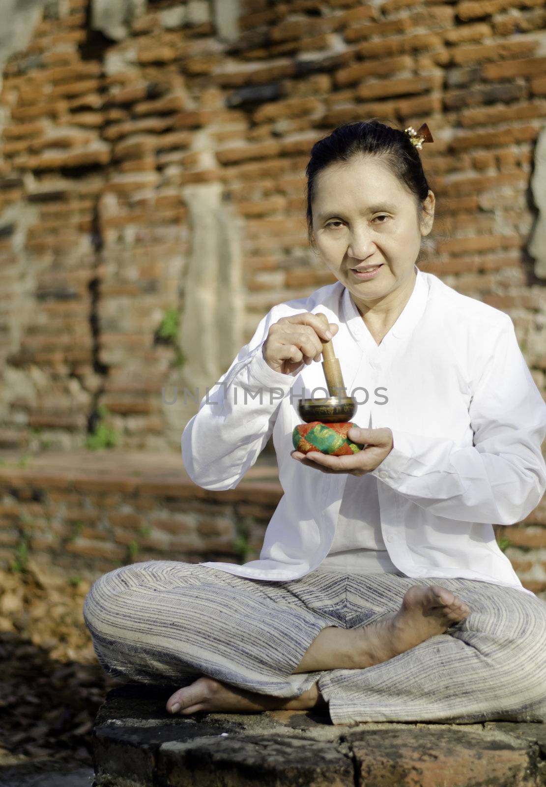 Woman playing a tibetan bowl,  traditionally used to aid meditation in Buddhist cultures. 