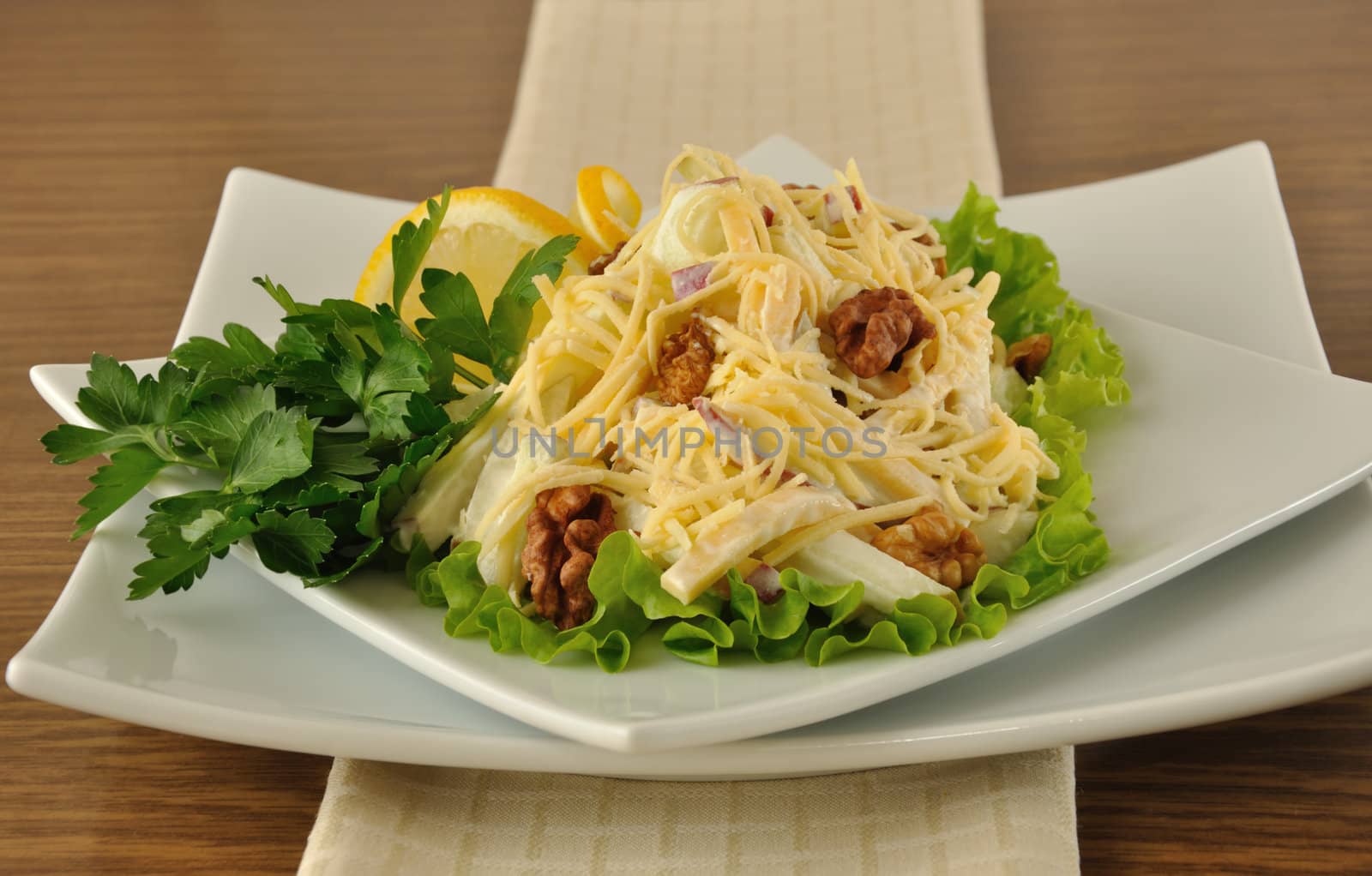 Salad with cheese and apple, walnuts and yogurt on lettuce leaves with lemon