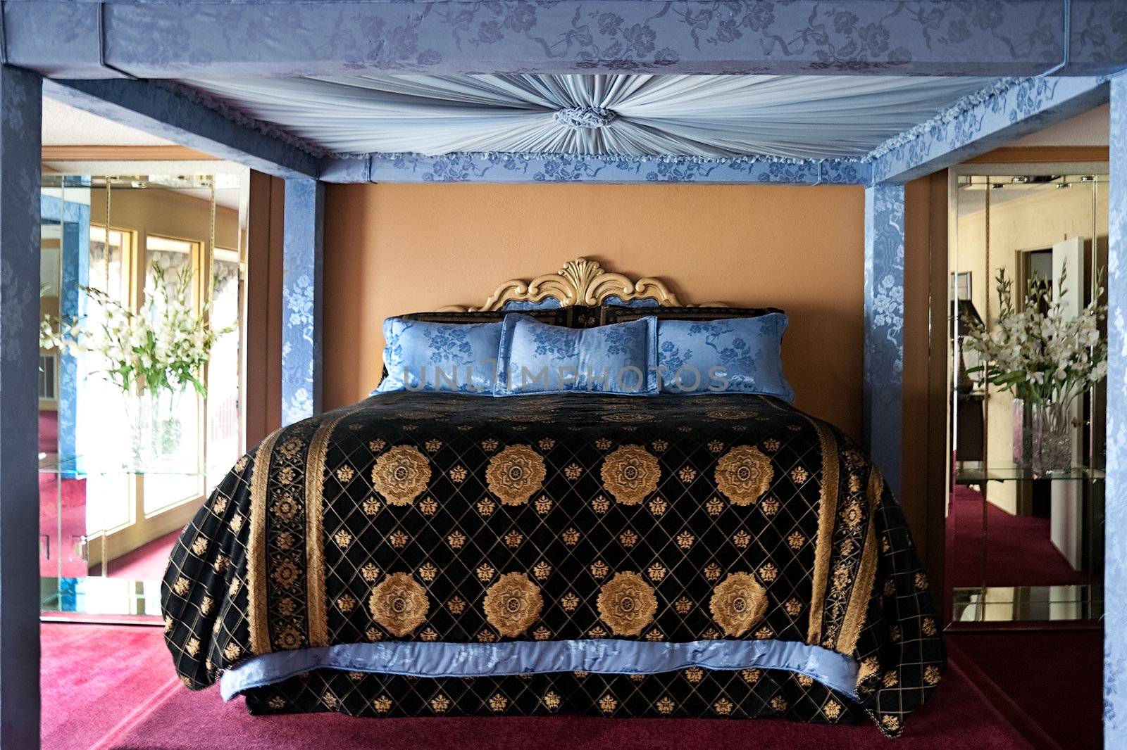 A large king bed with blue canopy and mirrors