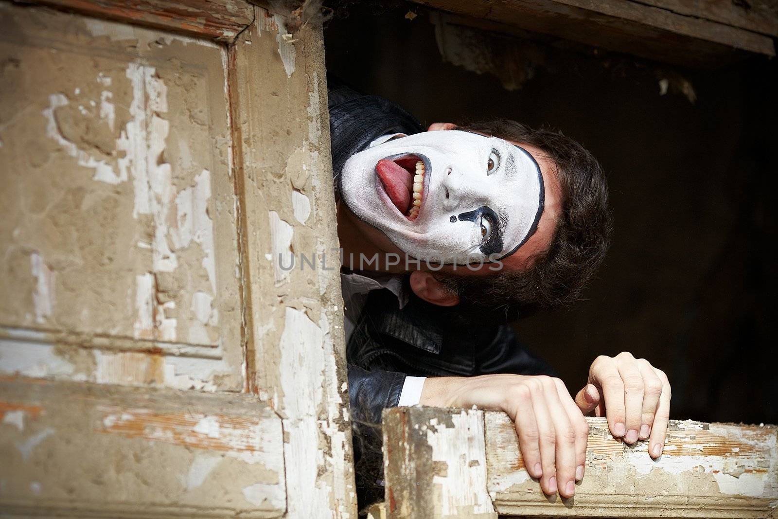 Portrait of a Man ​​mime. Grimacing near the old wooden door with peeling paint. Cocked his head