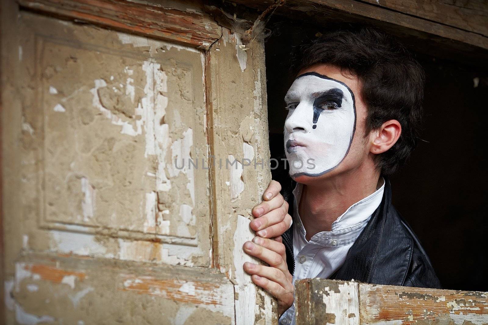 Portrait of a Man ​​mime. Grimacing near the old wooden door with peeling paint