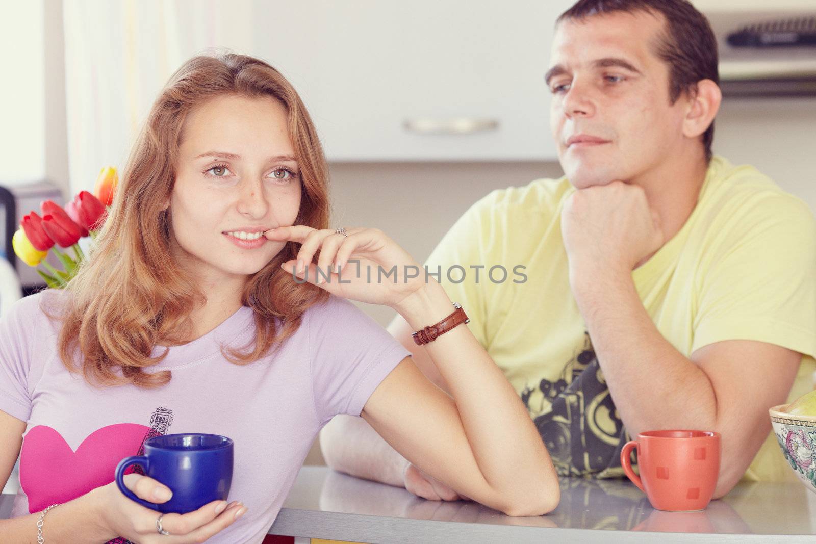 Couple in the kitchen drinking tea. Looks lovingly at his wife