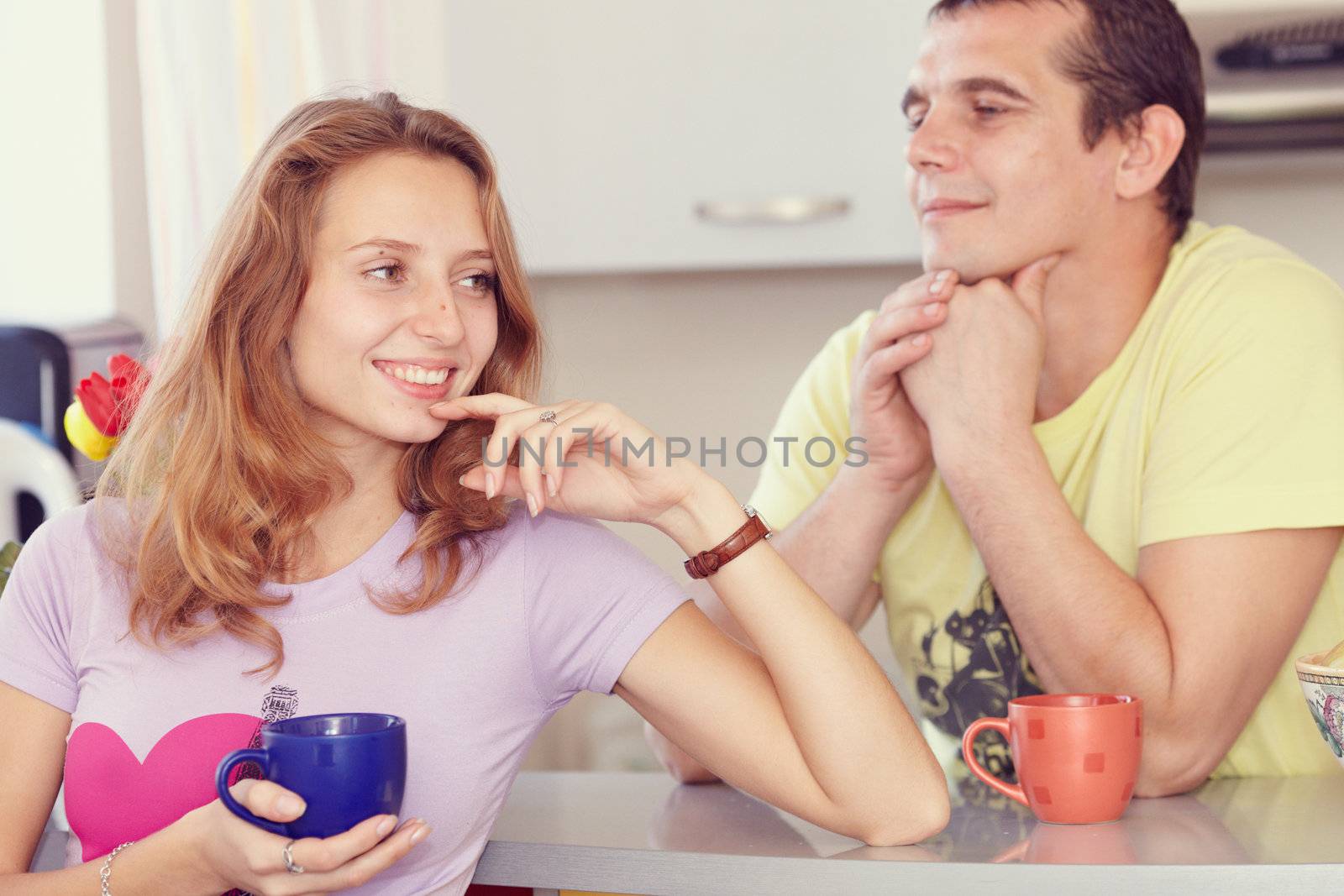 Couple in the kitchen drinking tea. Looks lovingly at his wife