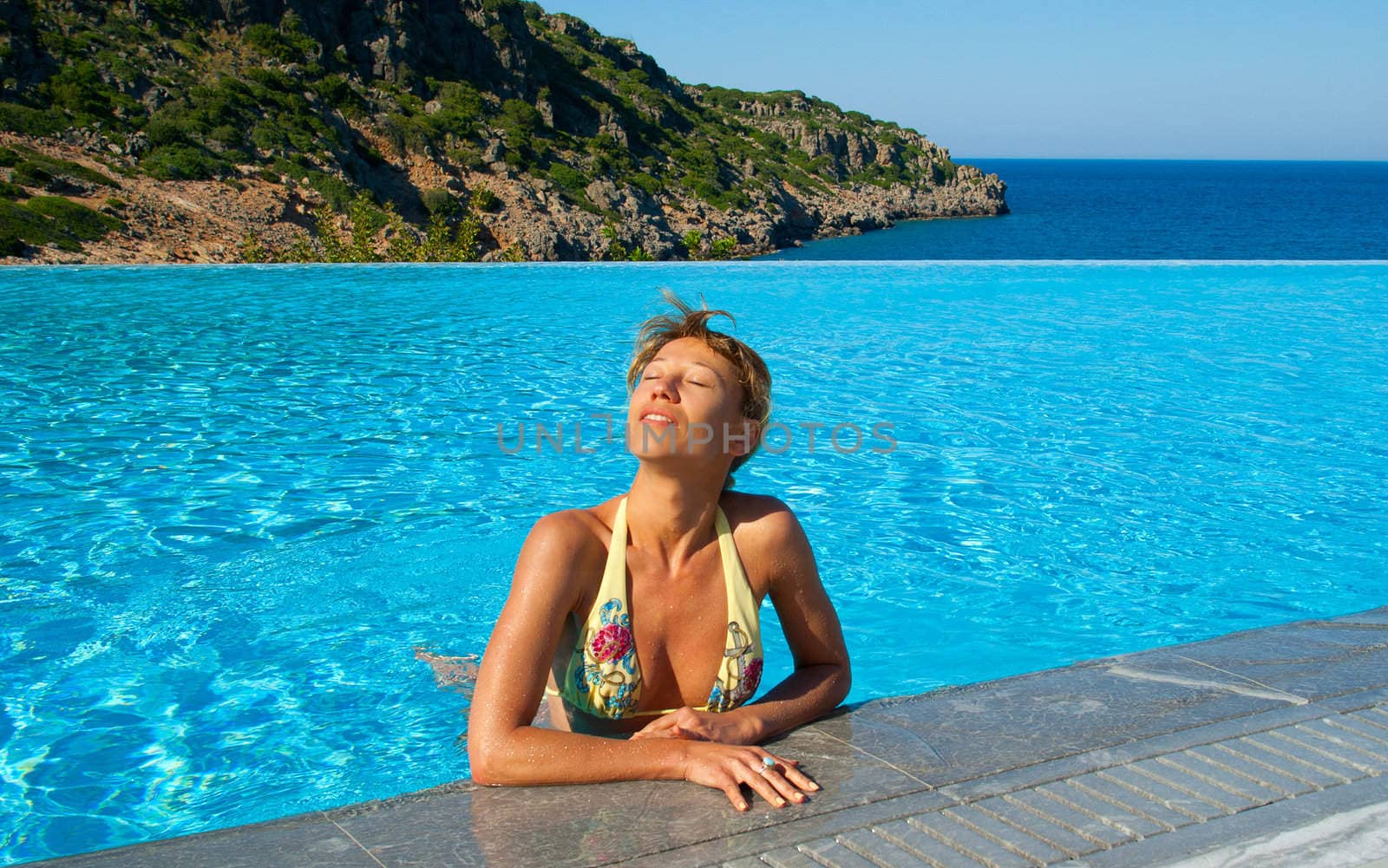 Beautiful woman suntanning in swimming pool near the Sea