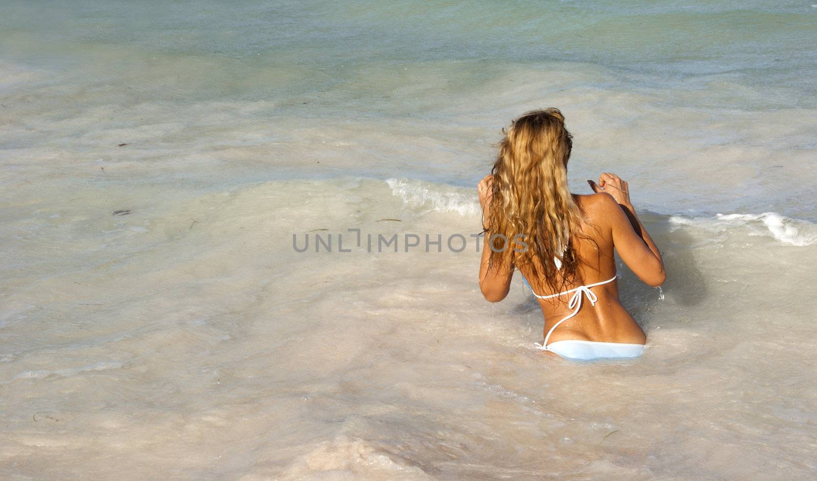 Beautiful woman in bikini going in the colorful sea in Dominican Republic