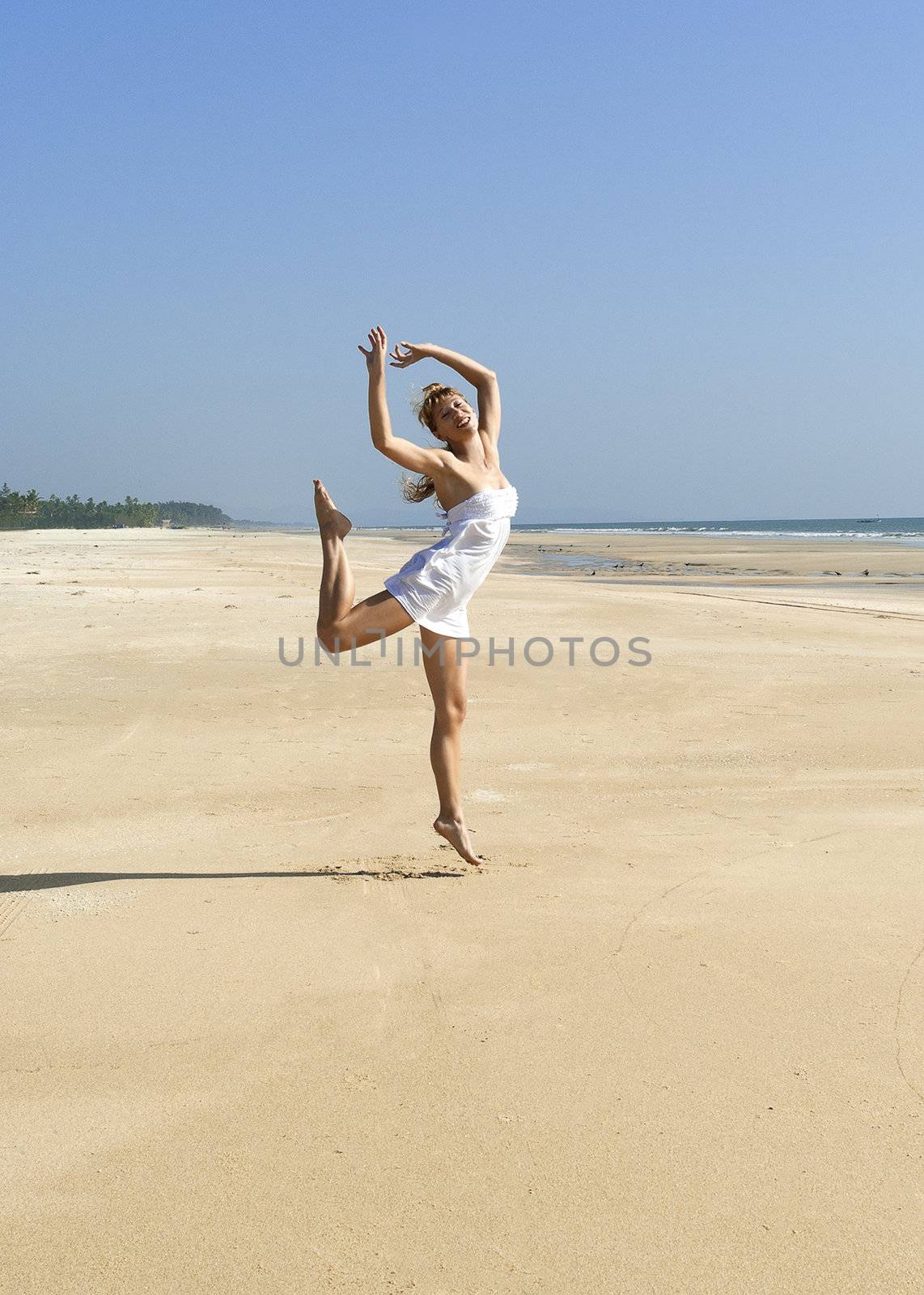 Happy woman dancing on sunny beach by Denovyi