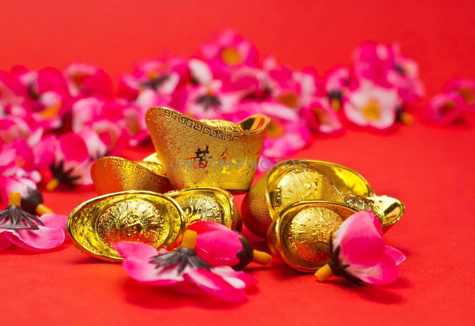 Golden Ingots with plum blosoms on red surface and background for Chinese New Year usage