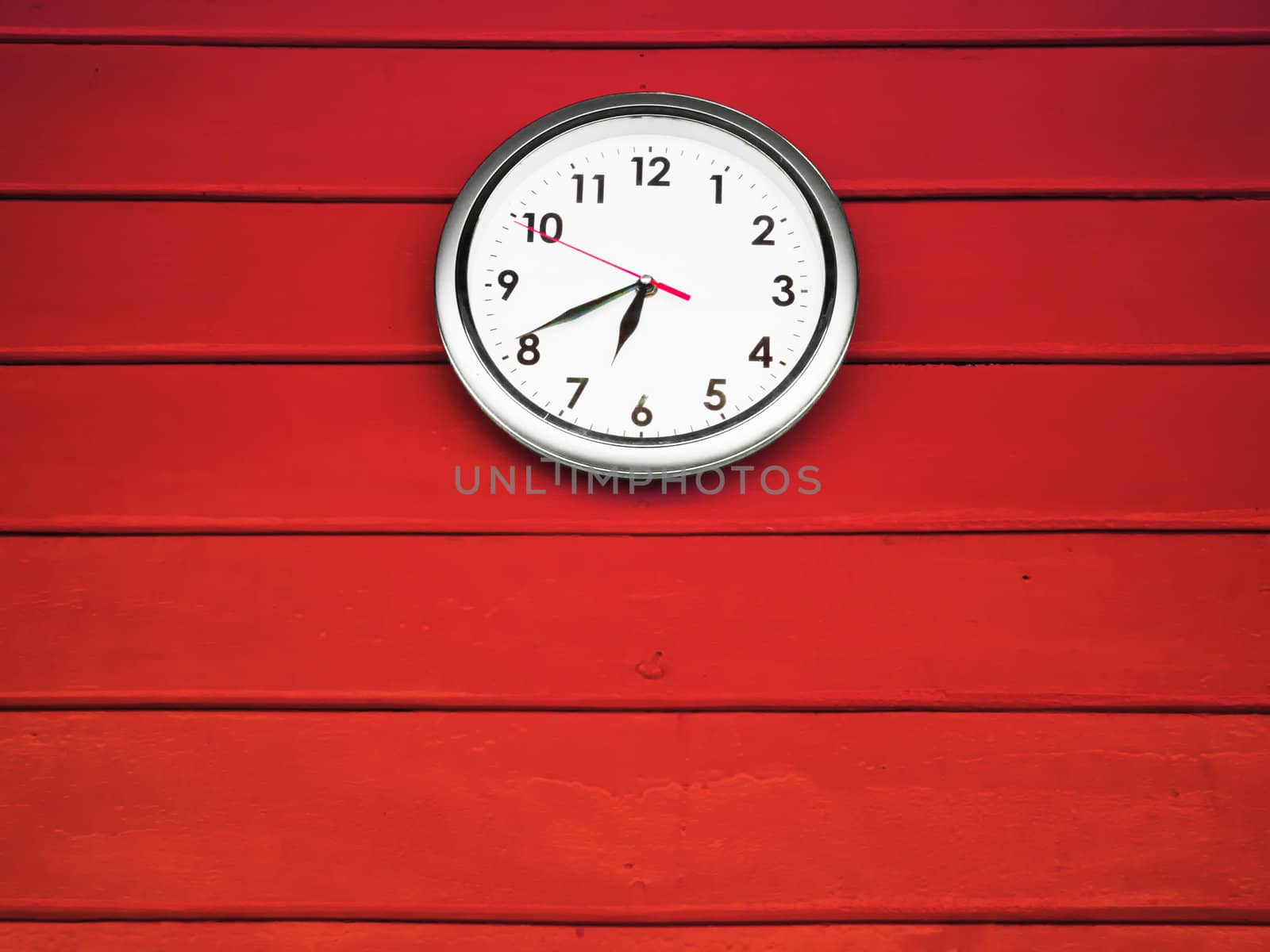 White silver clock hanging on Red wood wall