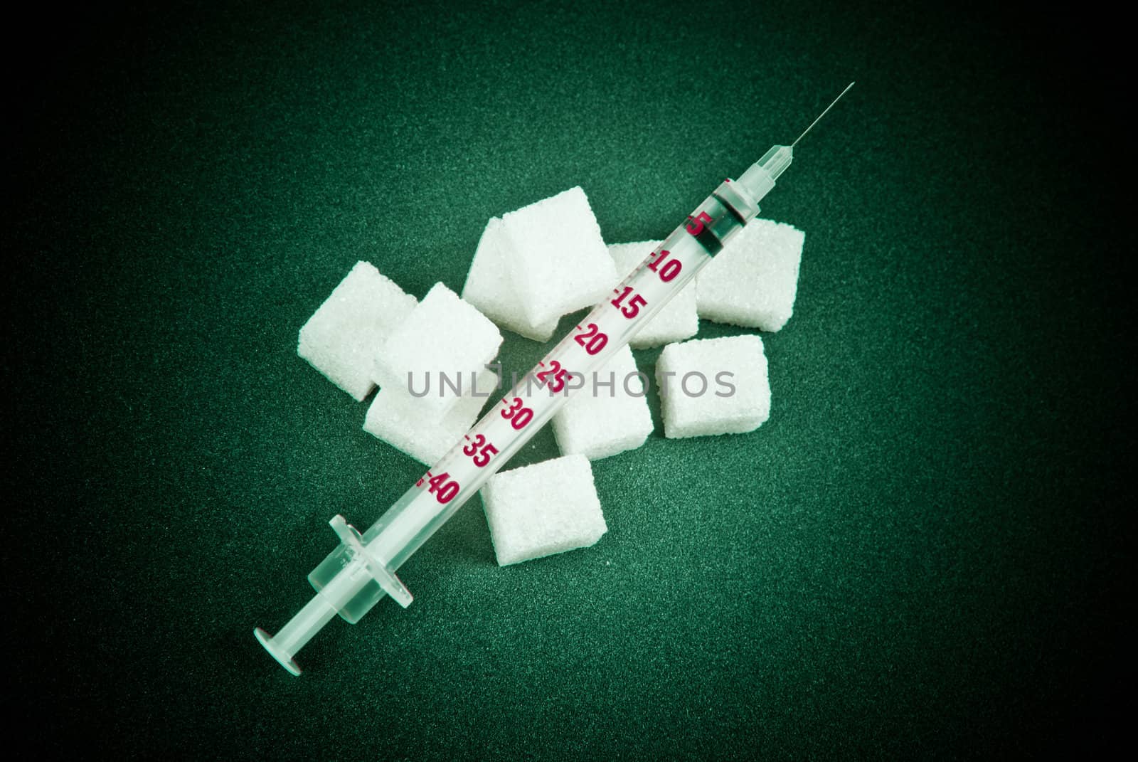 Insulin dependence. Insulin syringe and sugar on a green background.