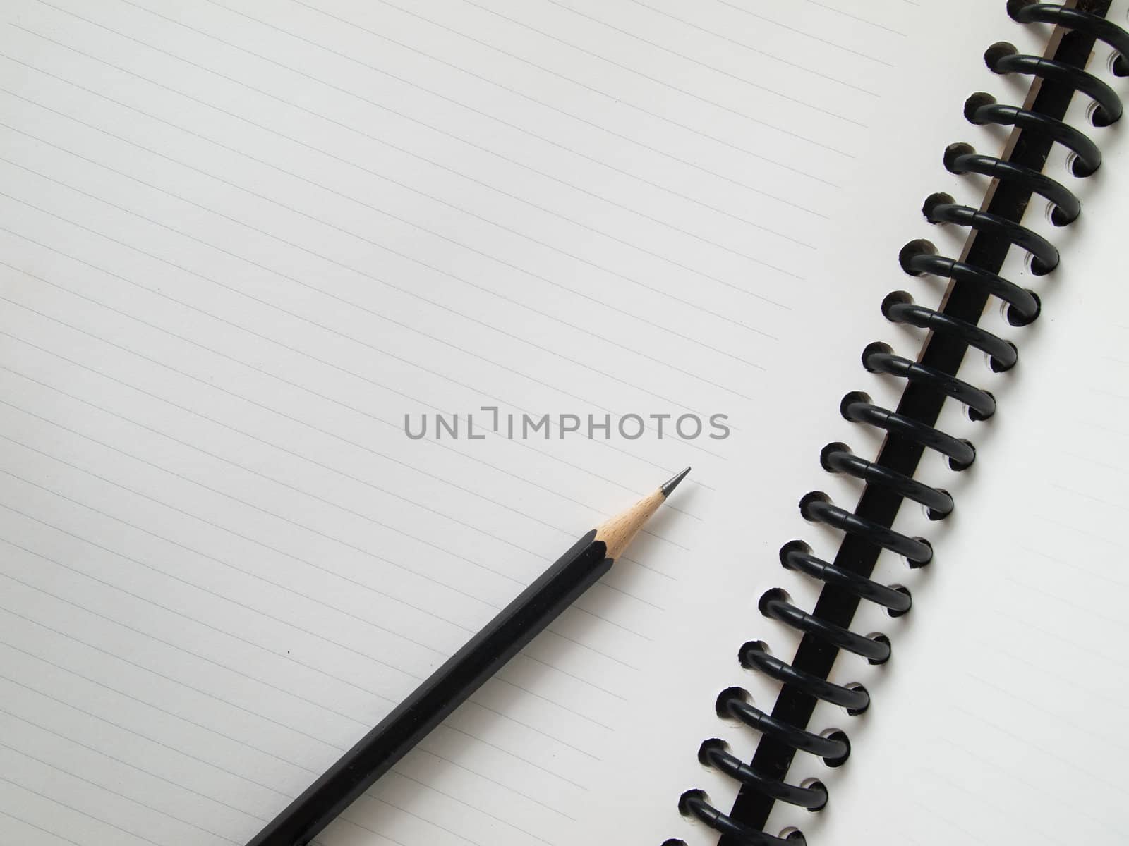 Black pencil on open white paper by nuttakit