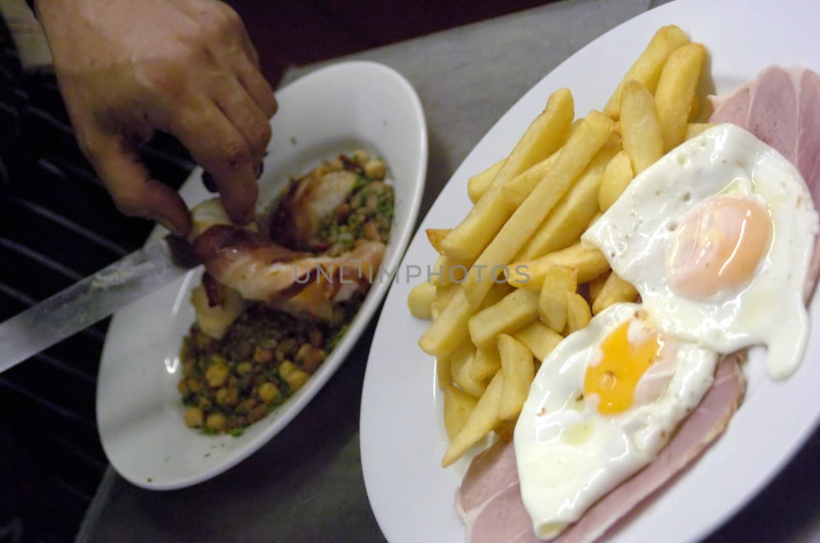 chef finishing off dishes in front the typical english british pub food ham eggs and chips
