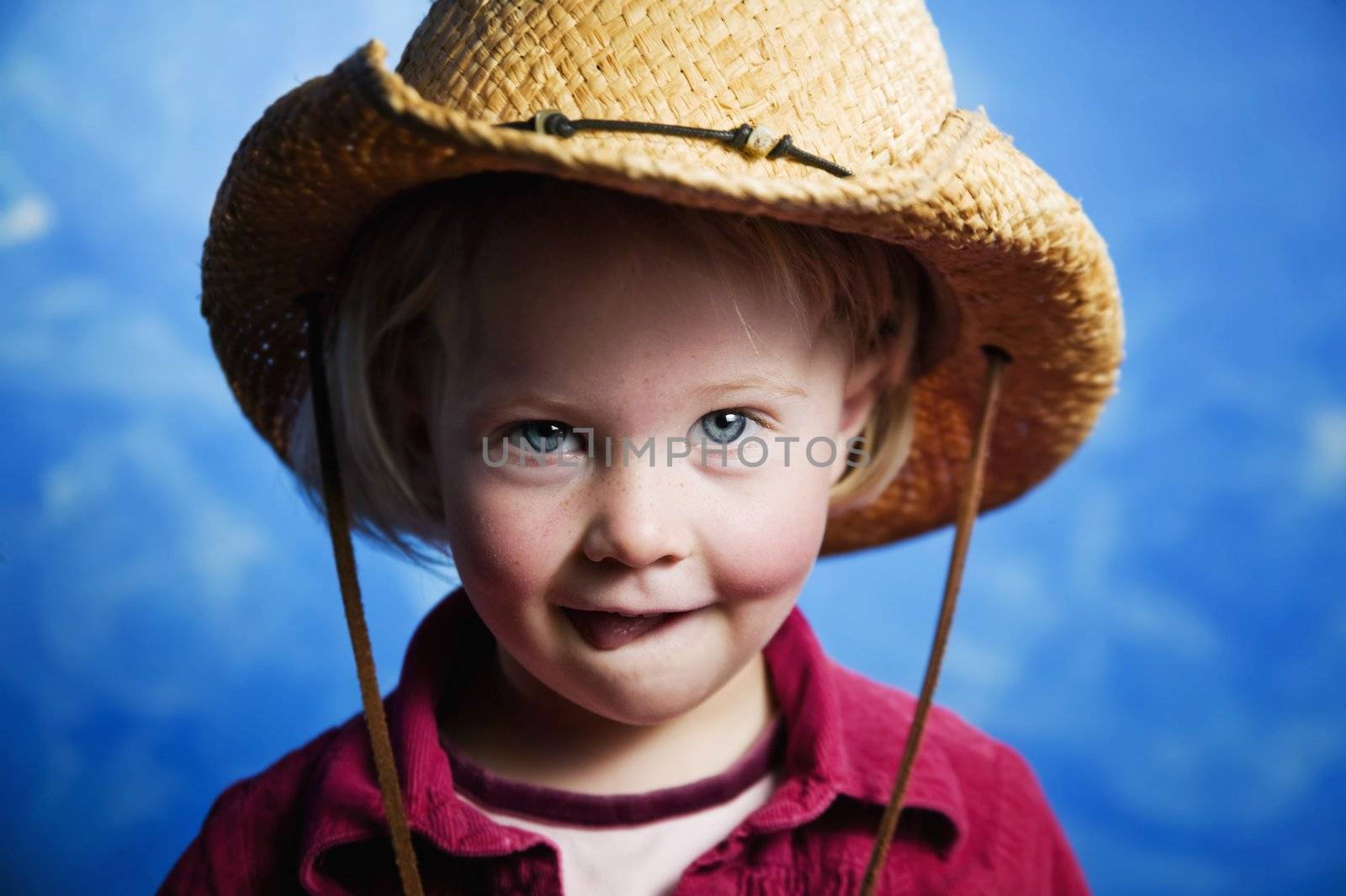 Little girl in front of blue wall with a cowboy hat by Creatista