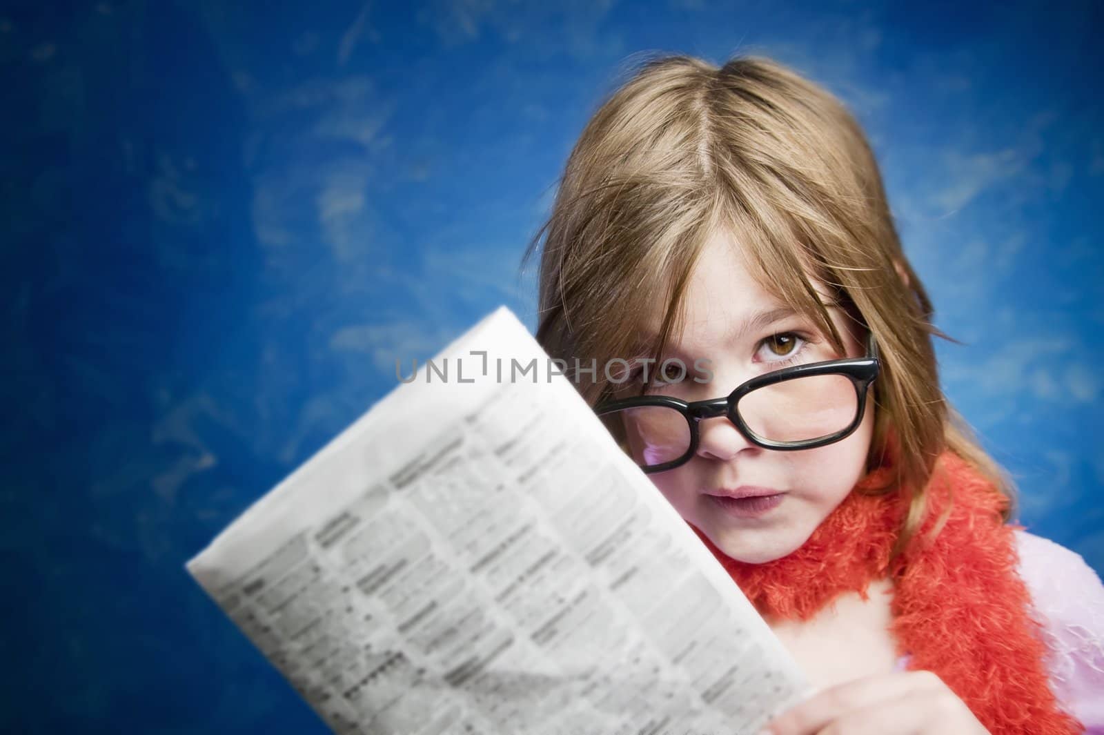 Young Girl Dressed Up in Reading Glasses Reading a Newspaper