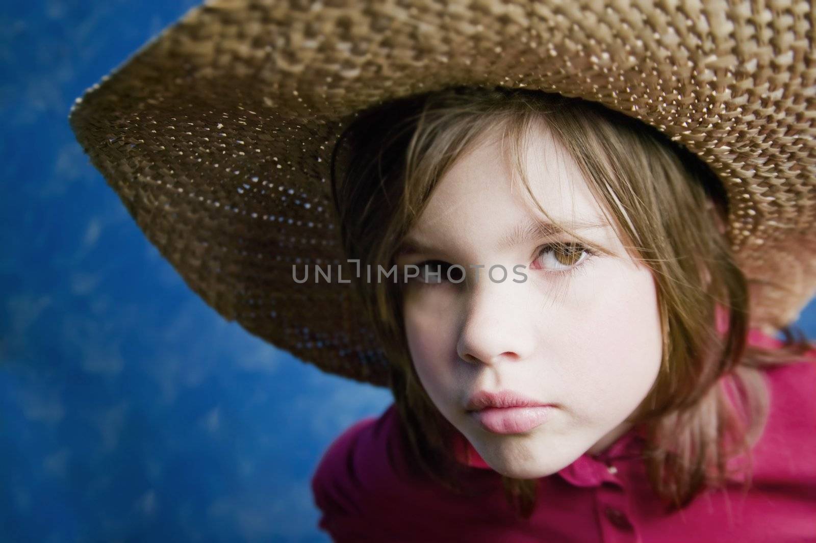 Little girl wearing a straw cowboy hat with a neutral expression