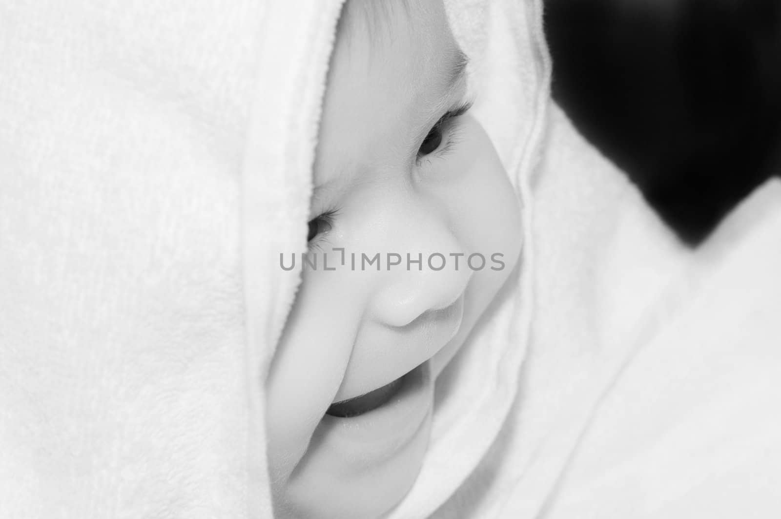 baby looking out and smiling from under blanket