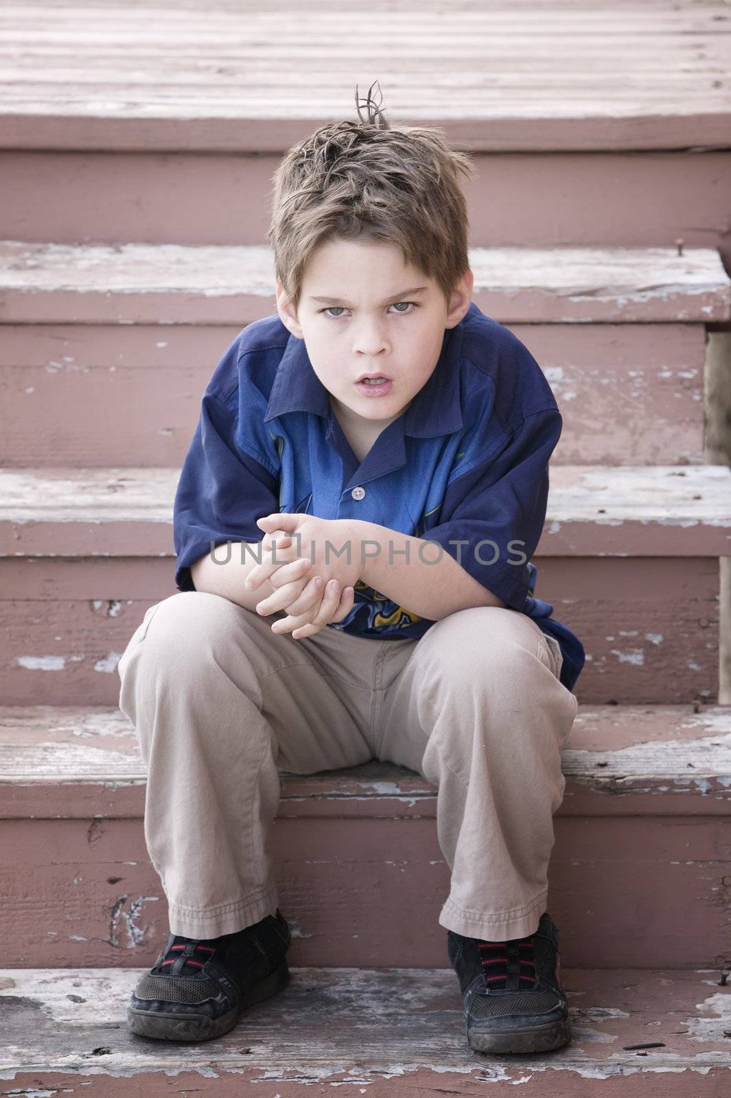 Grumpy Young Boy Sitting on Peeling Stairs