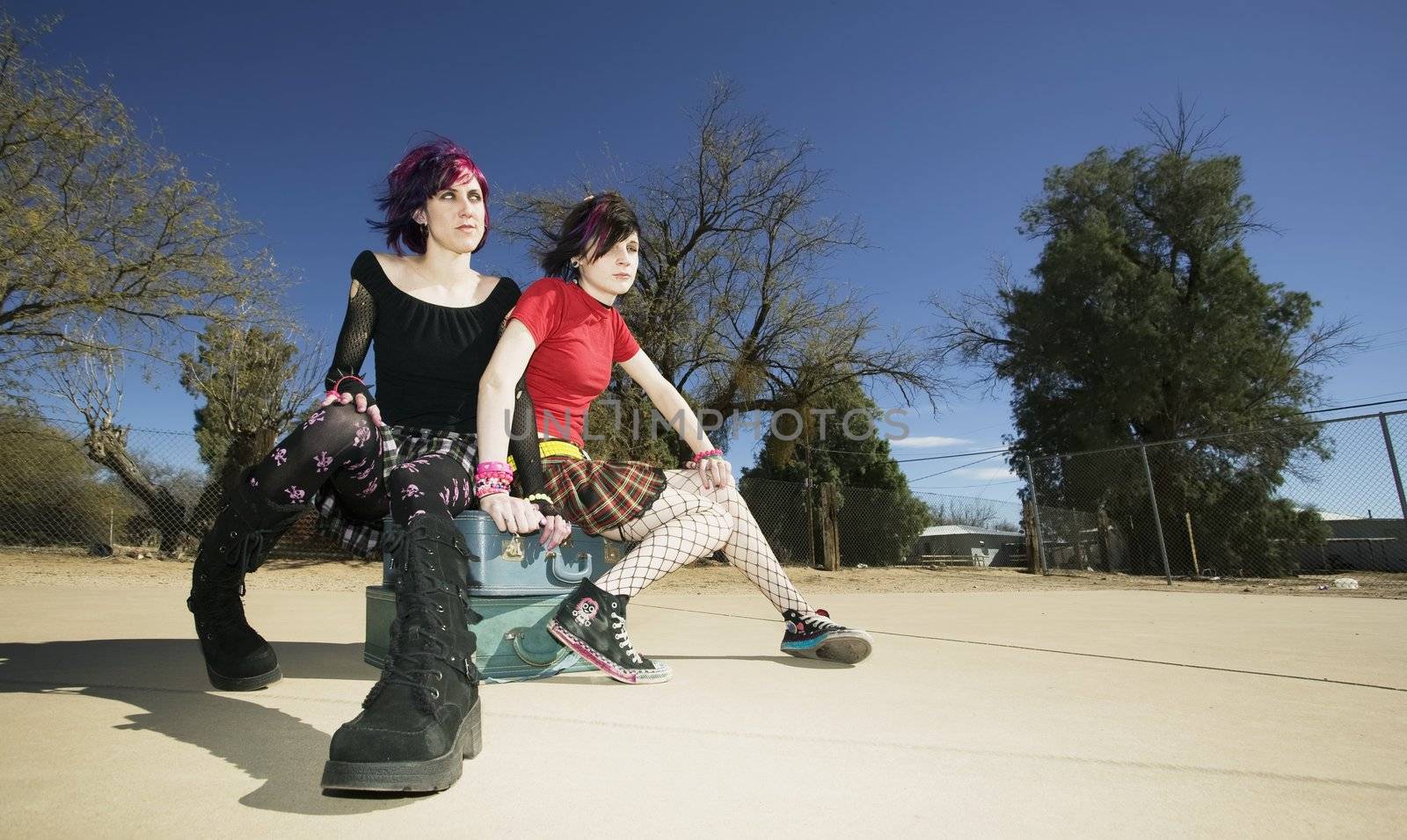 Two Punk Girls Sitting on Stacked Suitcases