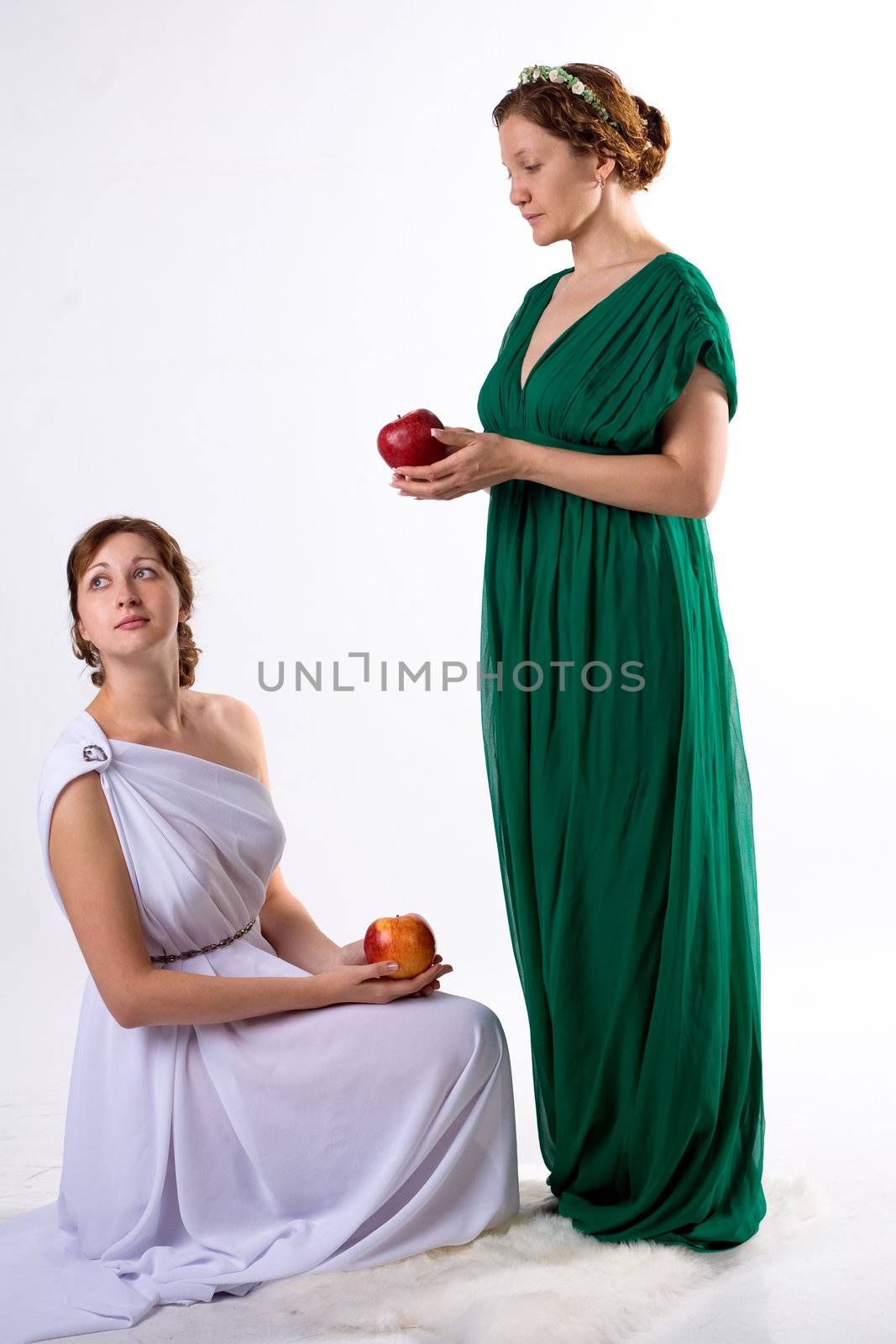 Two ladies in antique dress and two apples on white background
