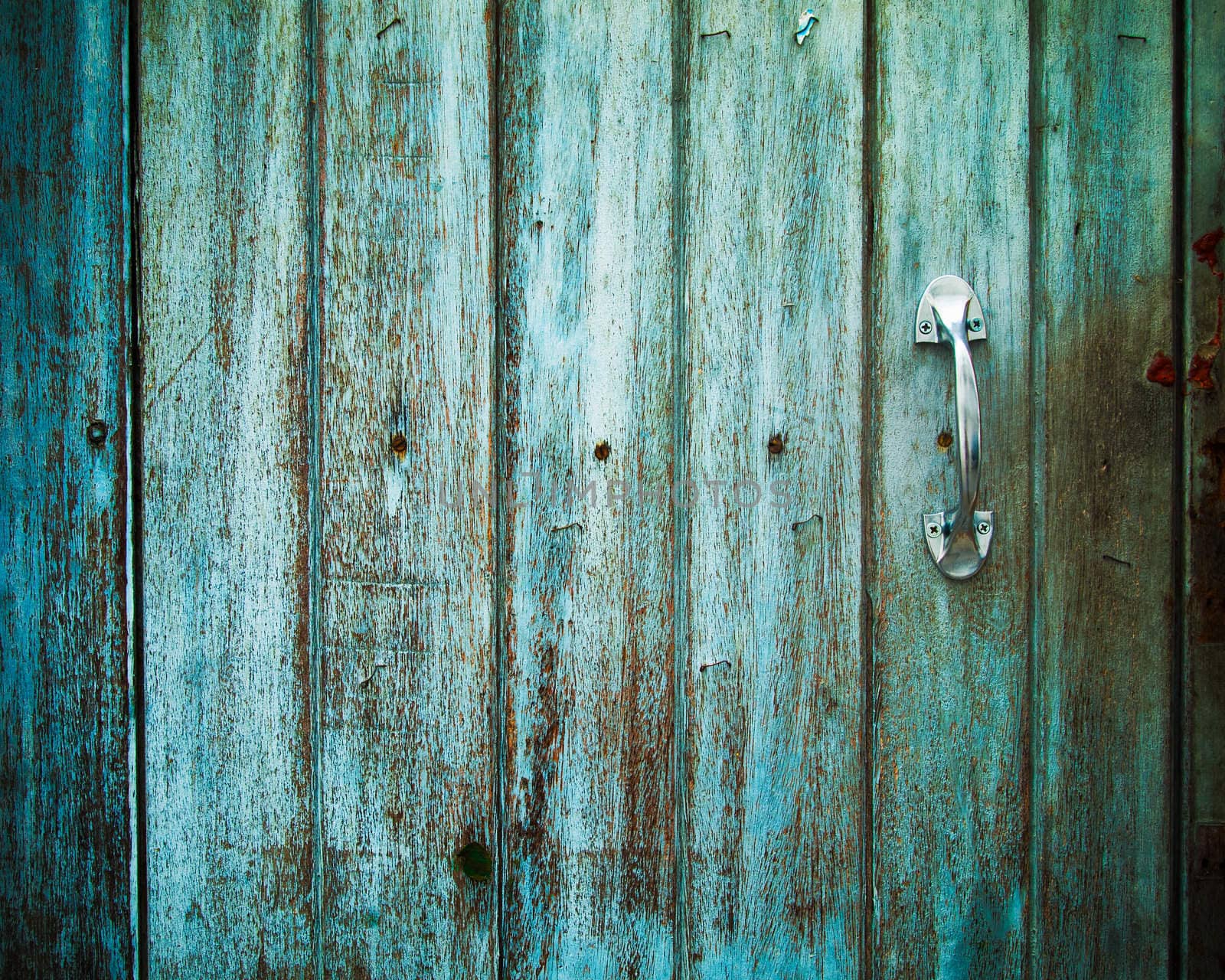 Old Door handle with an old wood door painted with green color