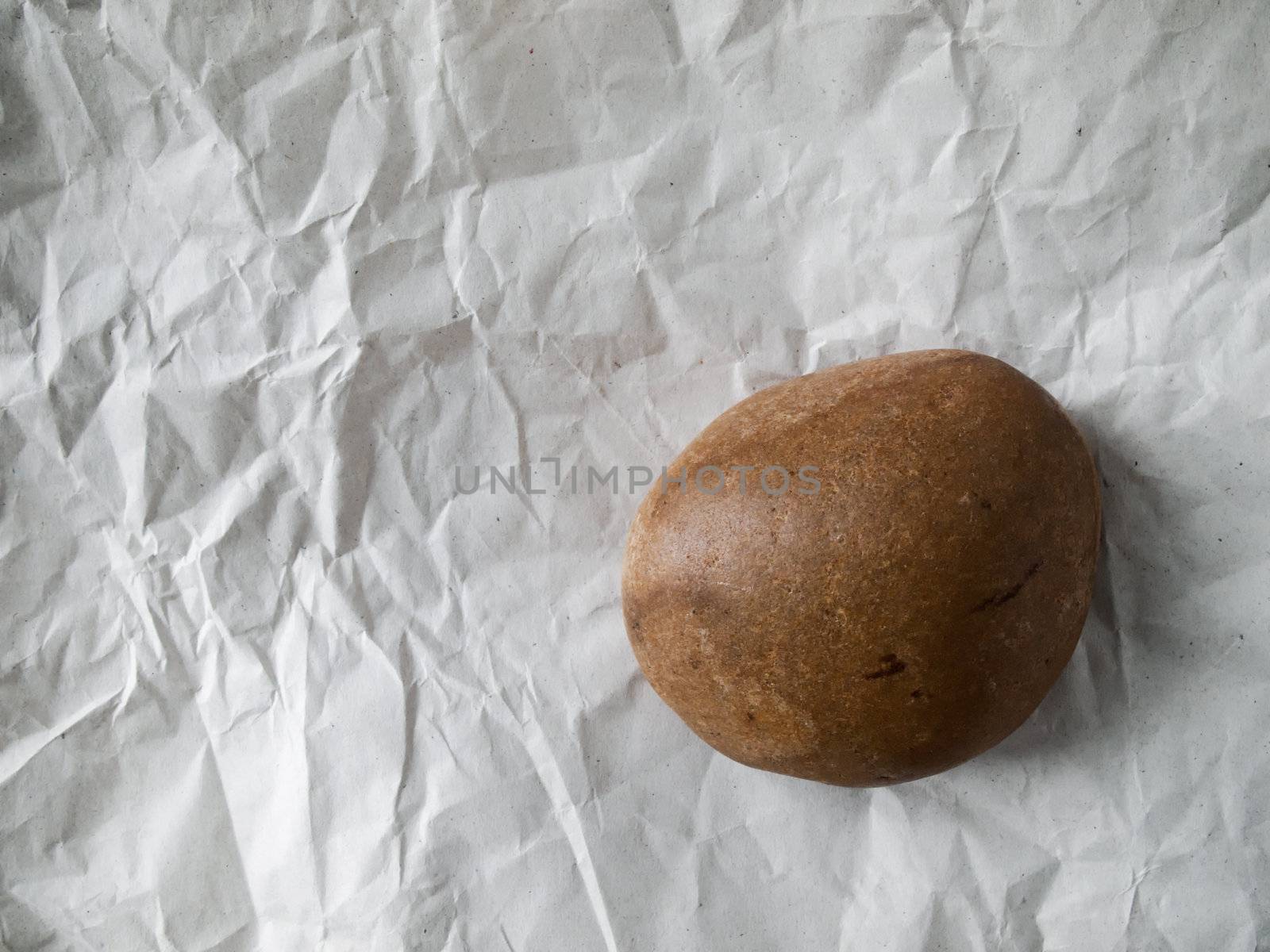 Brown round rock on white crumpled paper