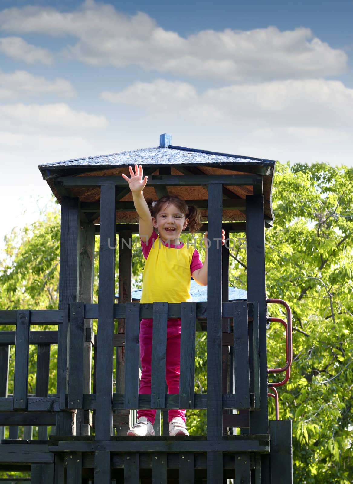 happy little girl on wooden tower playground by goce