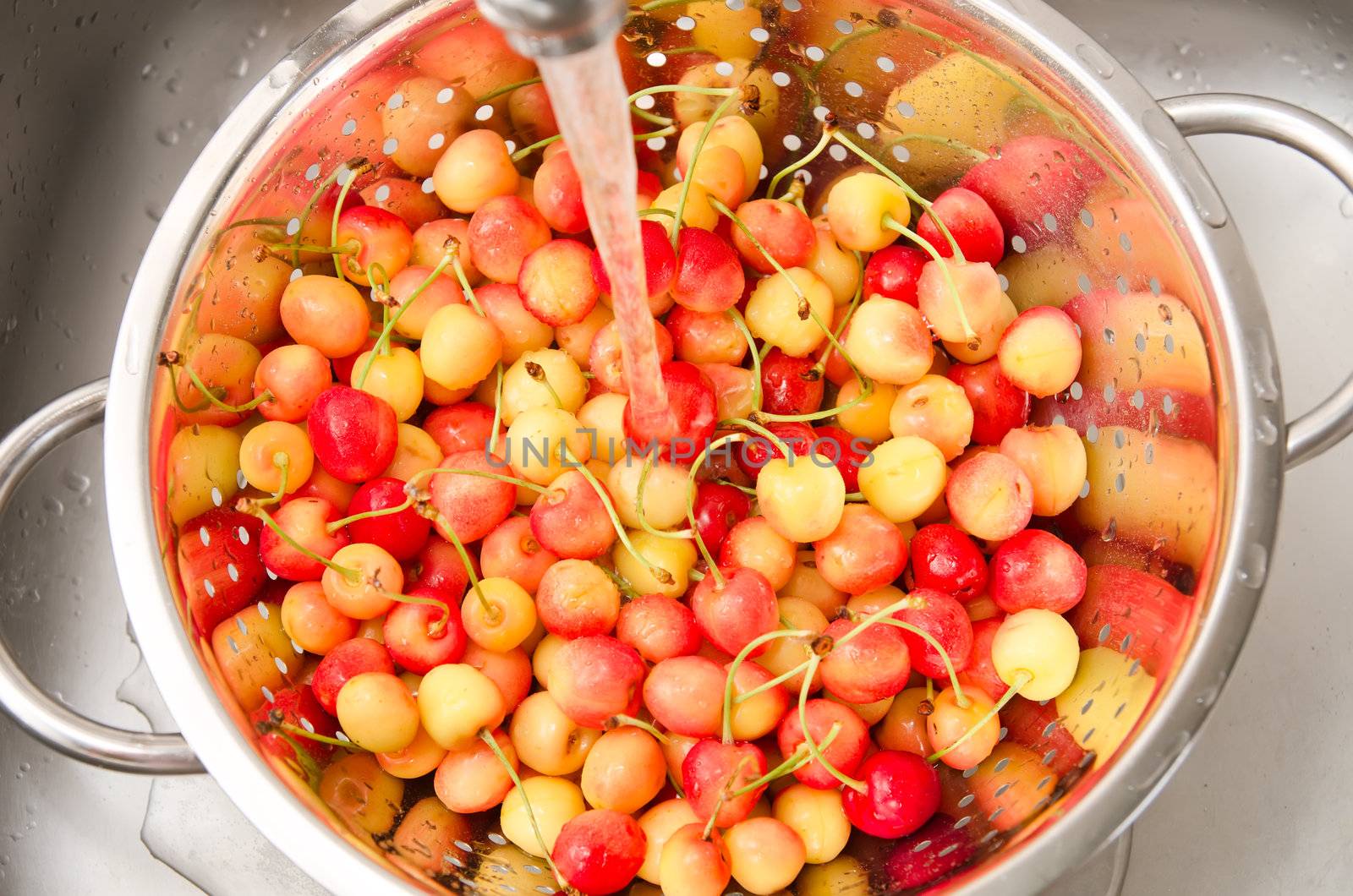 watering fresh cherry in colander