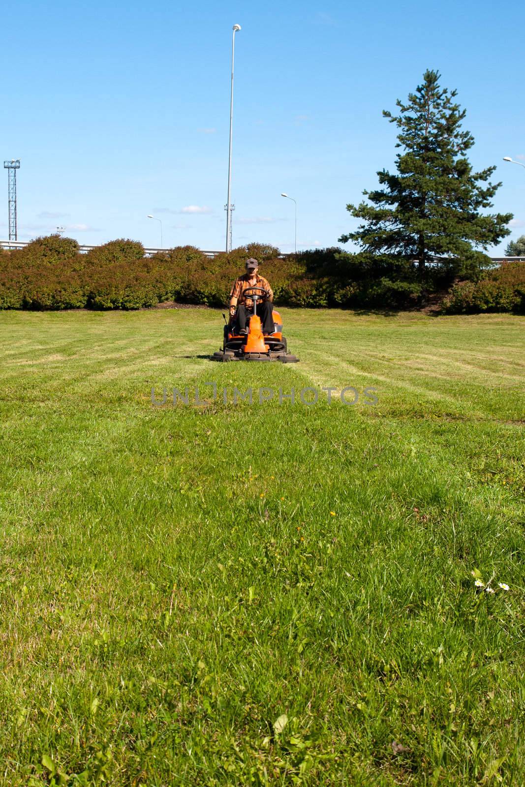 Mature man driving grass cutter in a sunny day
