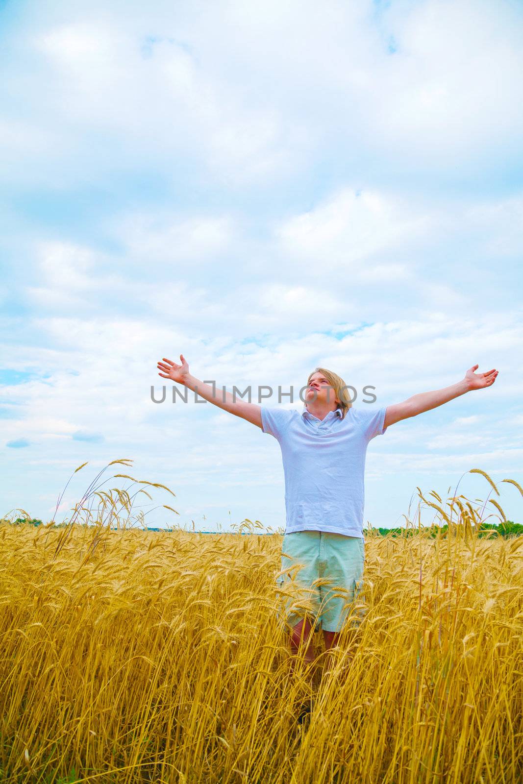 Young man staying with raised hands at sunset time