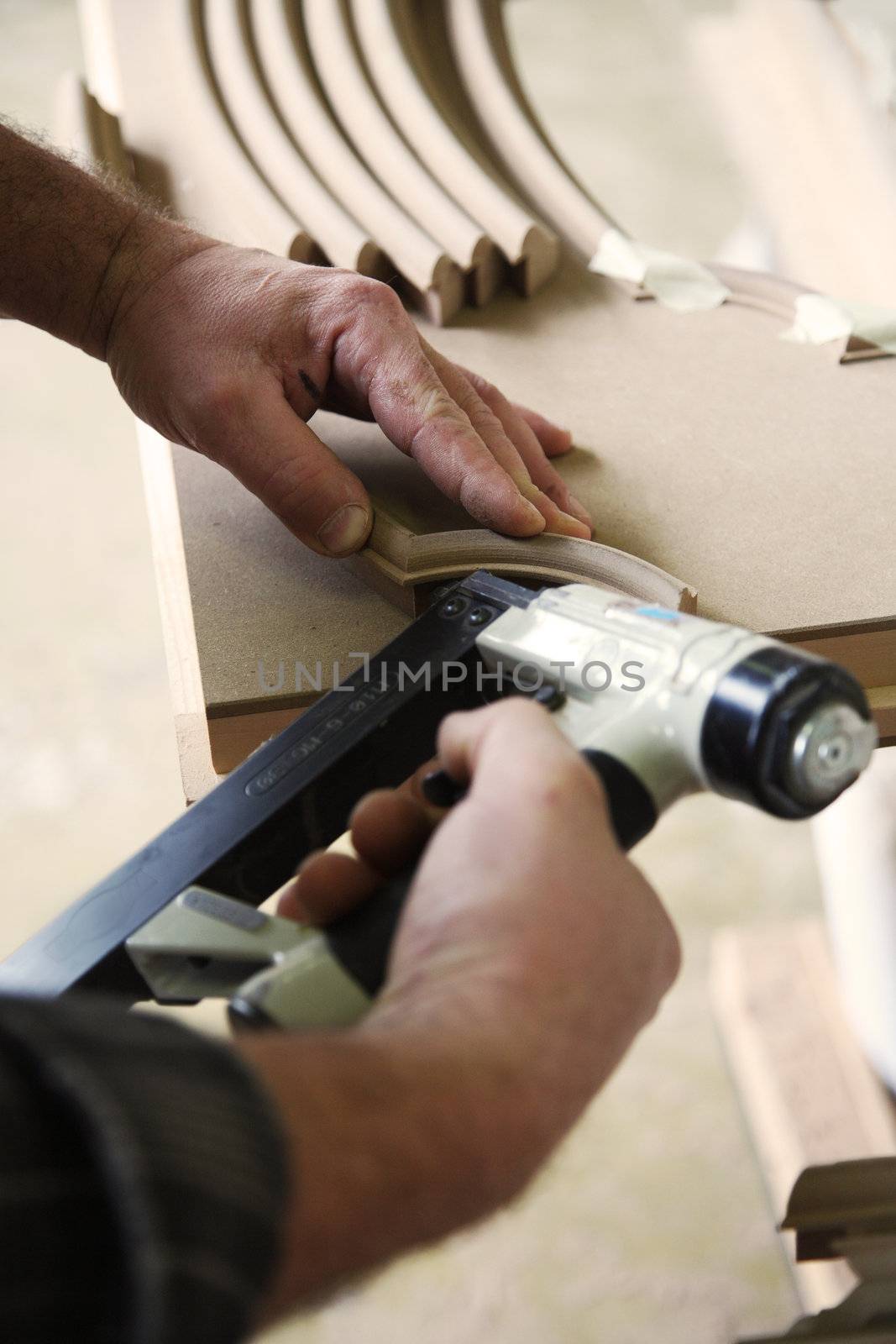 hands of a carpenter using a gun tacker air